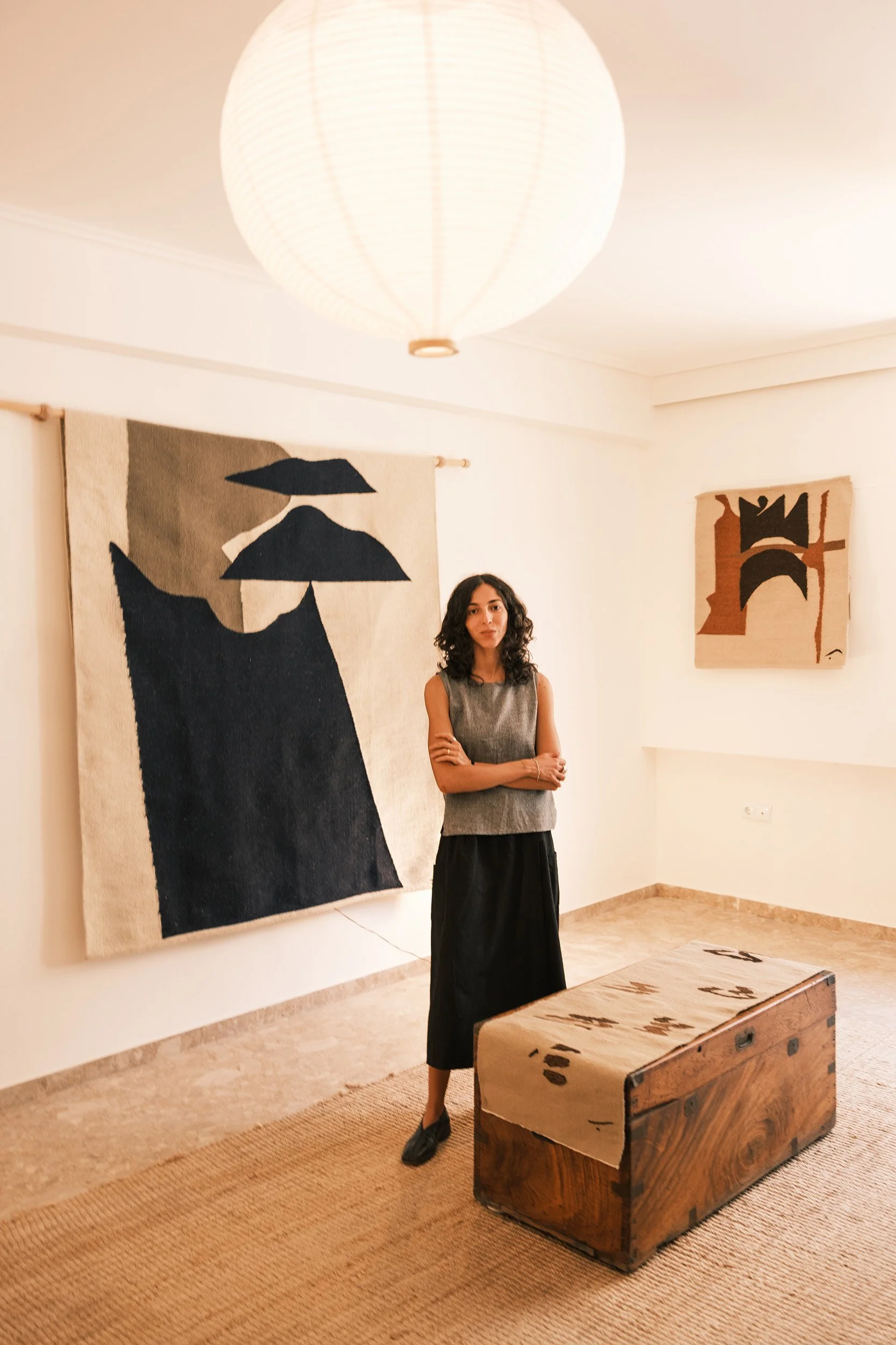 Salma Barakat in front of handmade rugs and tapestries