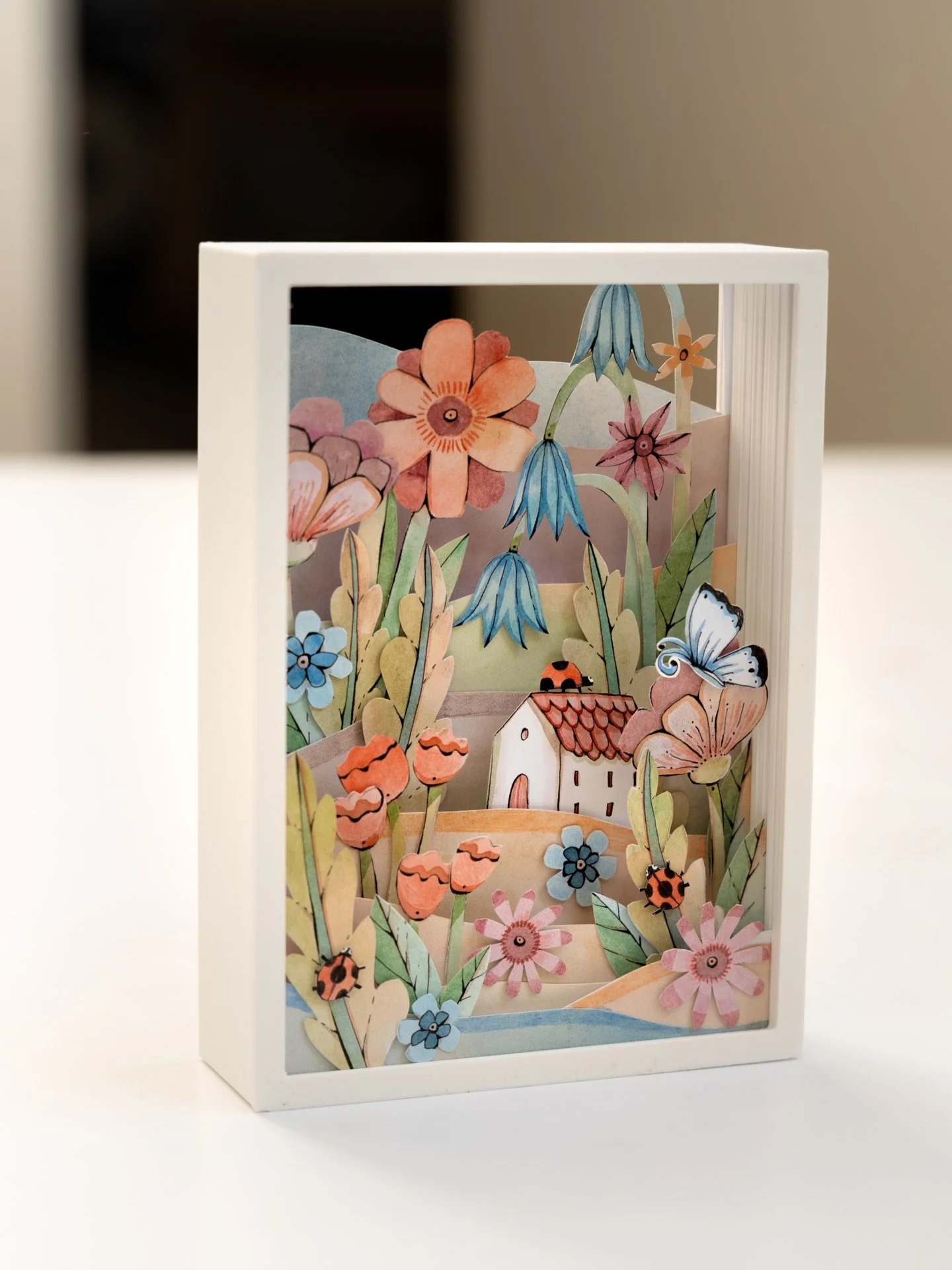 Seven layers of collage paper 🐞 And yes - I turned it into a template so you can print, cut, and colour it yourself ✂️

This little shadow box is my way of welcoming spring - a tiny cottage surrounded by flowers, butterflies, and ladybugs, all in so