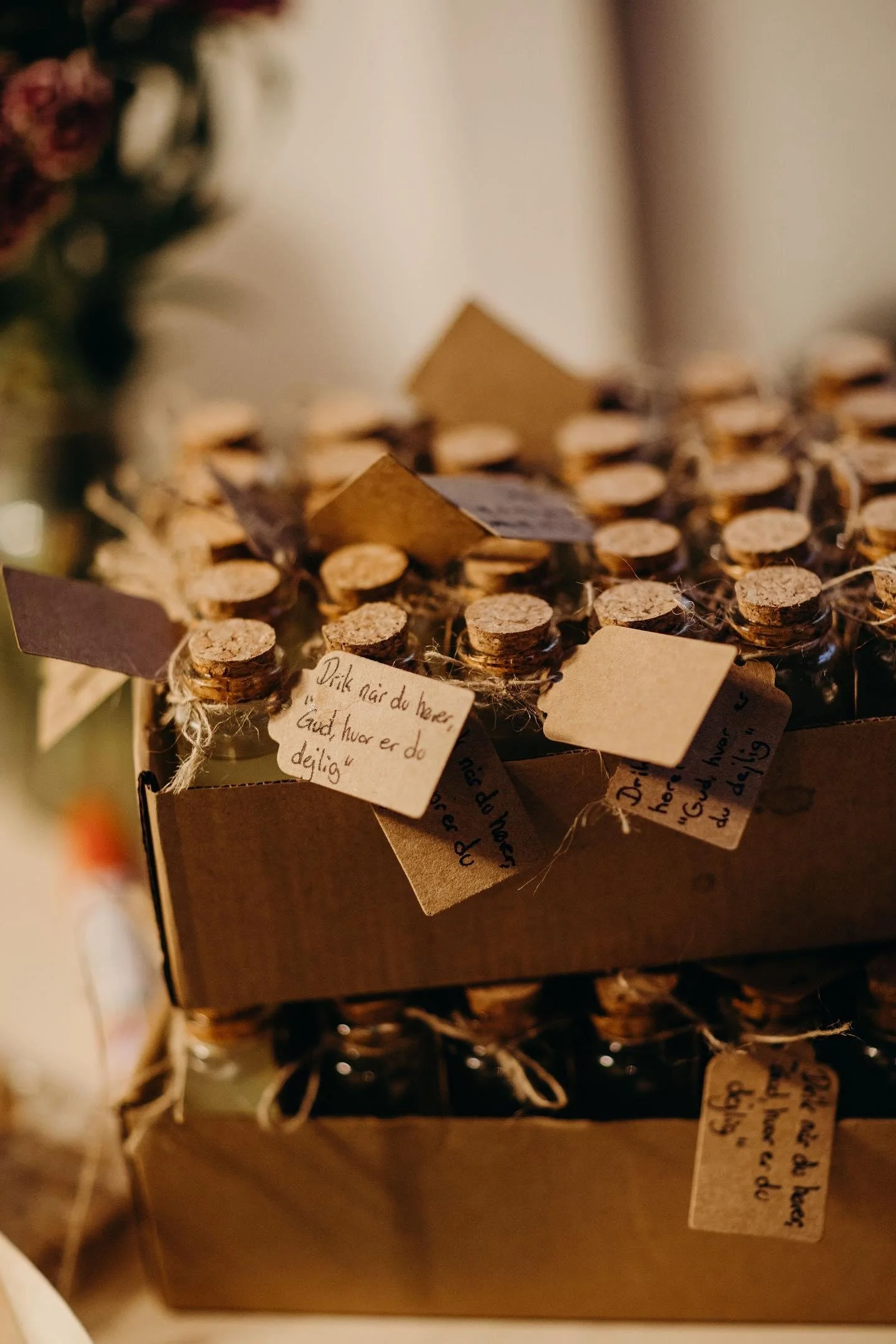 Småkager med tags og notater om indeholdte ingredienser, i en papkasse, lysebrune og små, lavet til gaver eller festligheder.