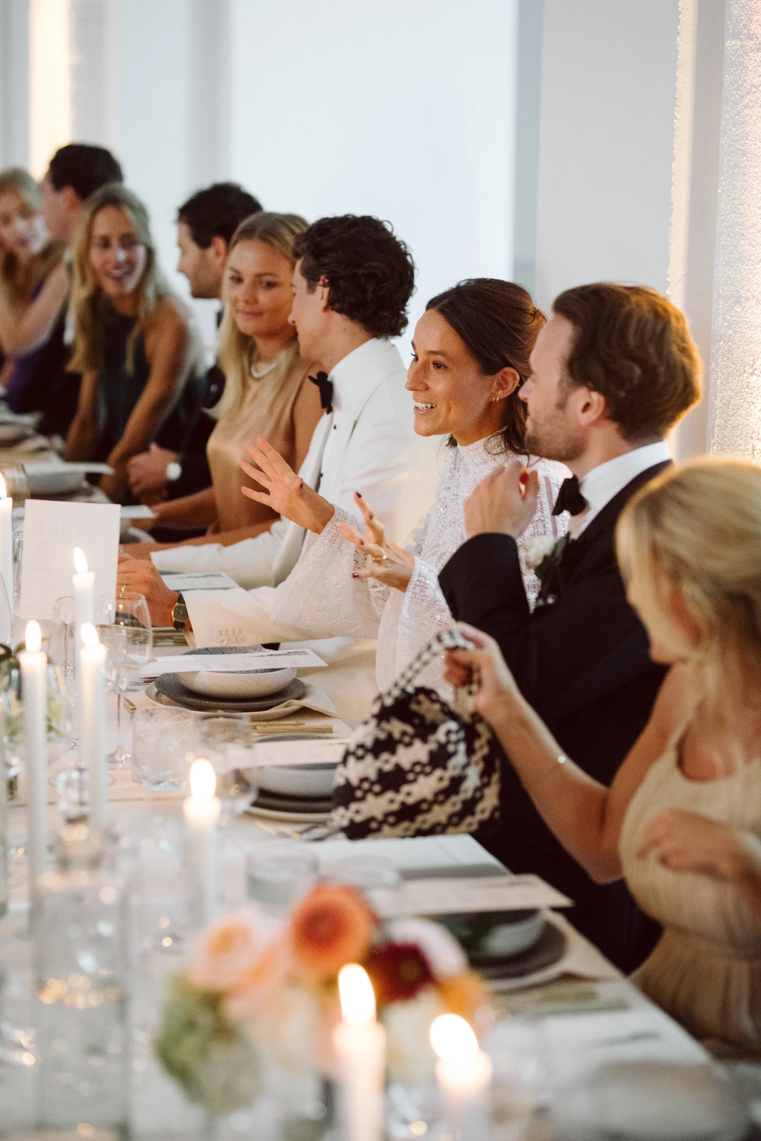 En bryllupsgruppe sidder til et elegance bryllupsmiddag, pyntet med stearinlys og blomster.