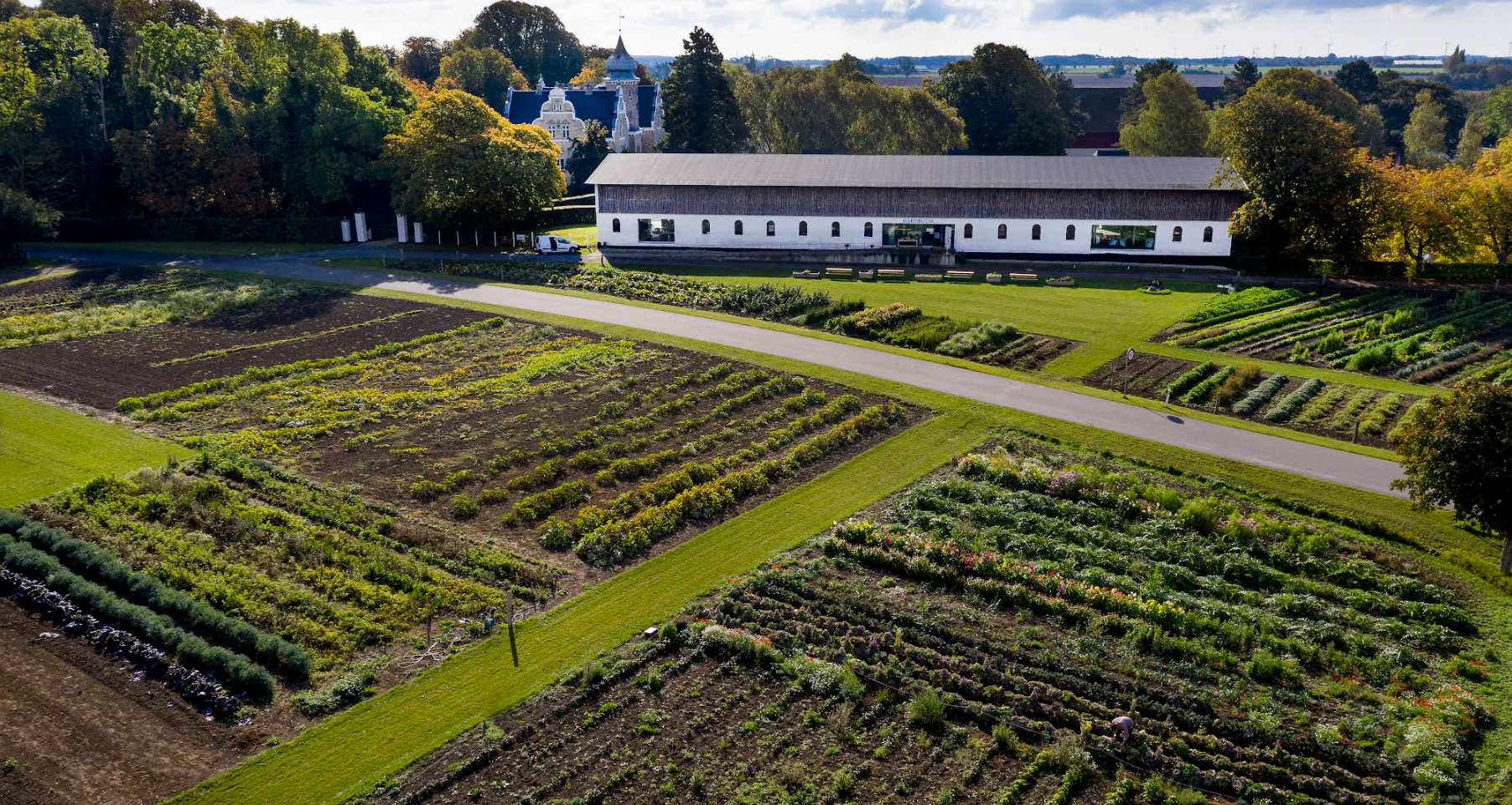 Bliss Cph - Søllestegård, marker, en lang hvid moderne bryllupsted , en hest i en have, og en stor gammel slot i baggrunden.