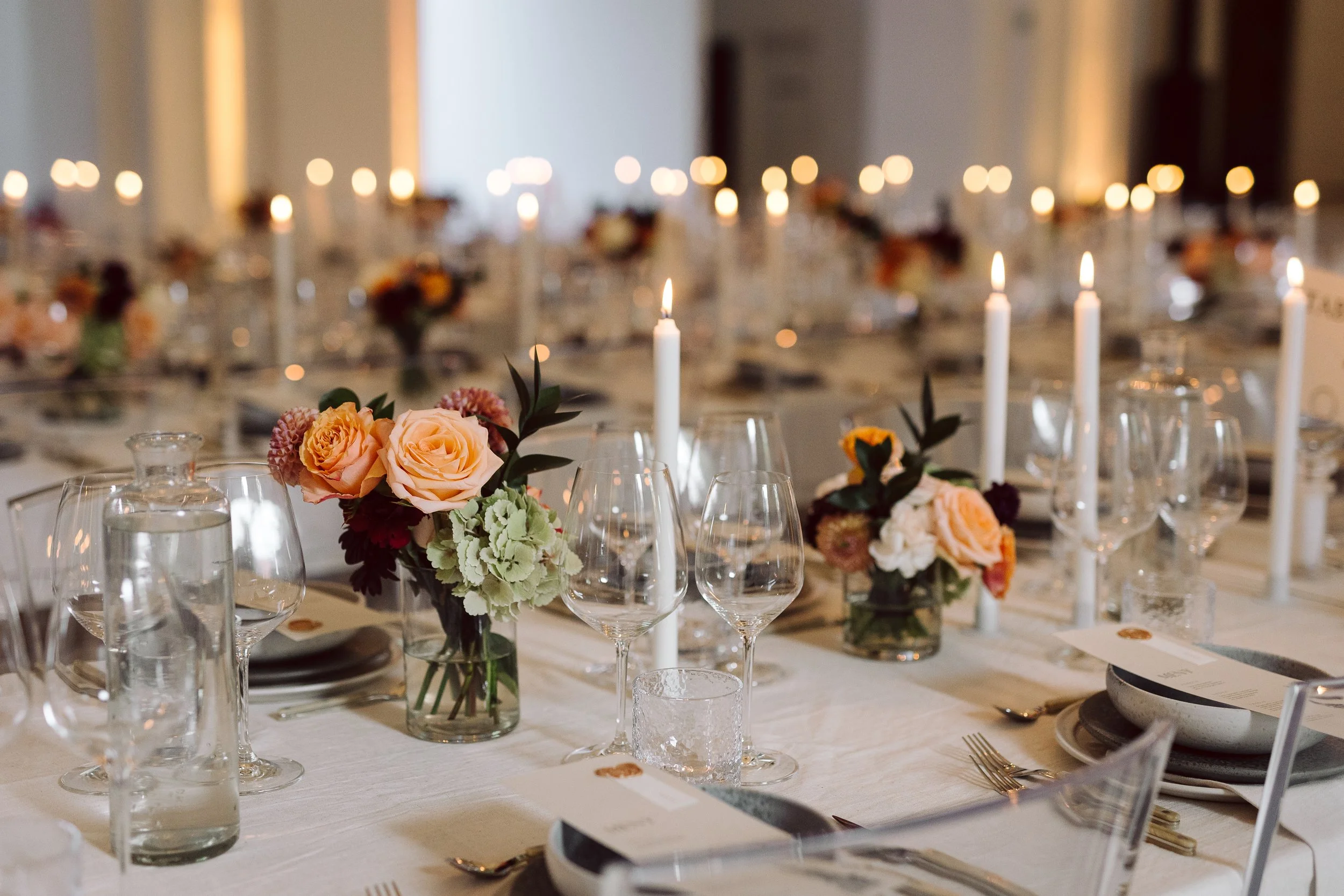Elegante festbord med blomsterdekorationer, stearinlys og glas, klar til en formel middag.