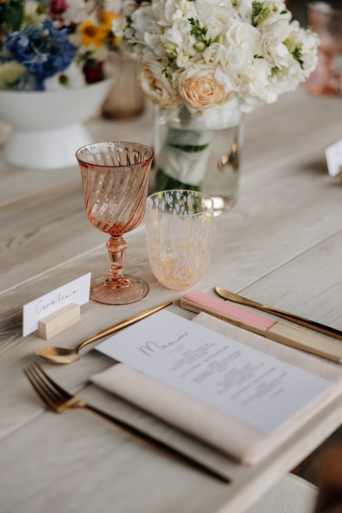 Bliss CPH – Bordopdækning med glas, bestik, menu, plads til navneskilt, blomsterdekoration med hvide og lyserøde blomster.