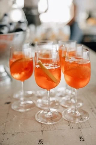 Tre glas med rosafarvet væske og citron- eller limebåde, sat på en bar eller bord.