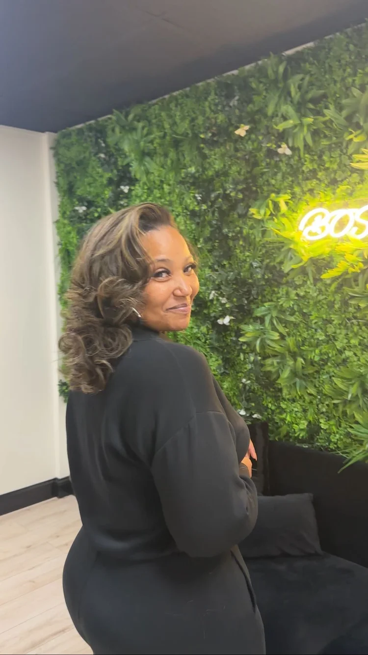 Inside Like A Boss Salon, in front of the green wall and neon sign