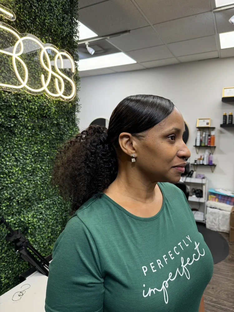 Sleek ponytail in front of the salon's BOSS neon sign