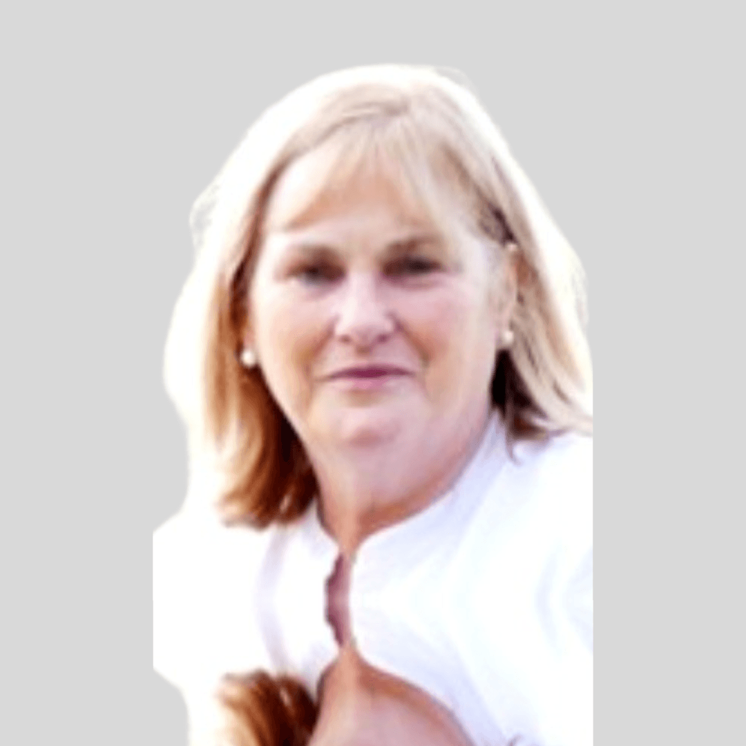 A woman with shoulder-length blonde hair, wearing a white top, looking at the camera against a plain, light background.