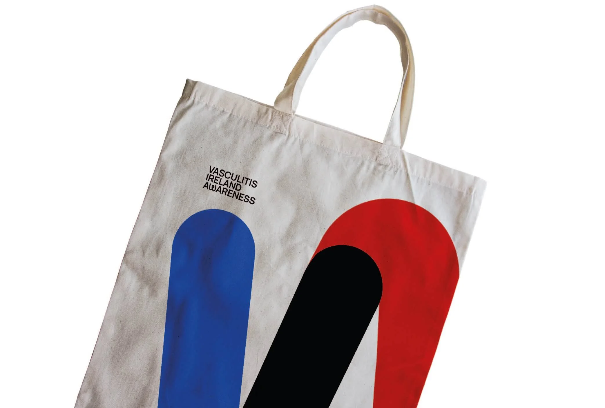White tote bag with blue, black, and red abstract shapes and text promoting Vasculitis Ireland Awareness.