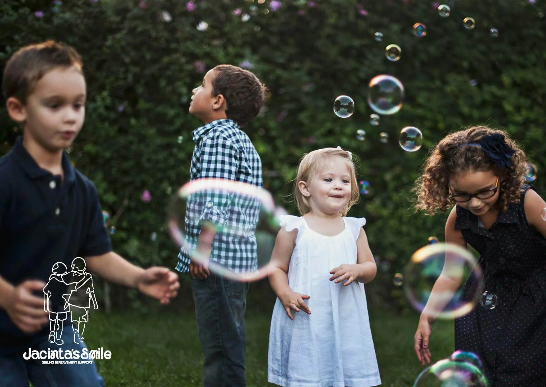 Four children playing outdoors with bubbles
