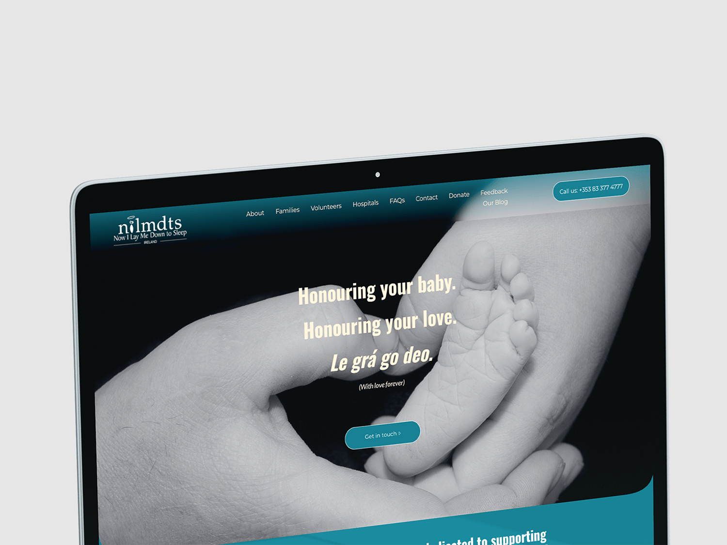 A website homepage for a charity organization supporting babies and families, featuring a black and white photo of a baby's hand holding an adult's finger, with a blue navigation bar and a call-to-action button.