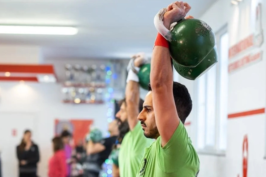Groupe de personnes soulevant des kettlebells lors d'un entraînement en salle de sport.
