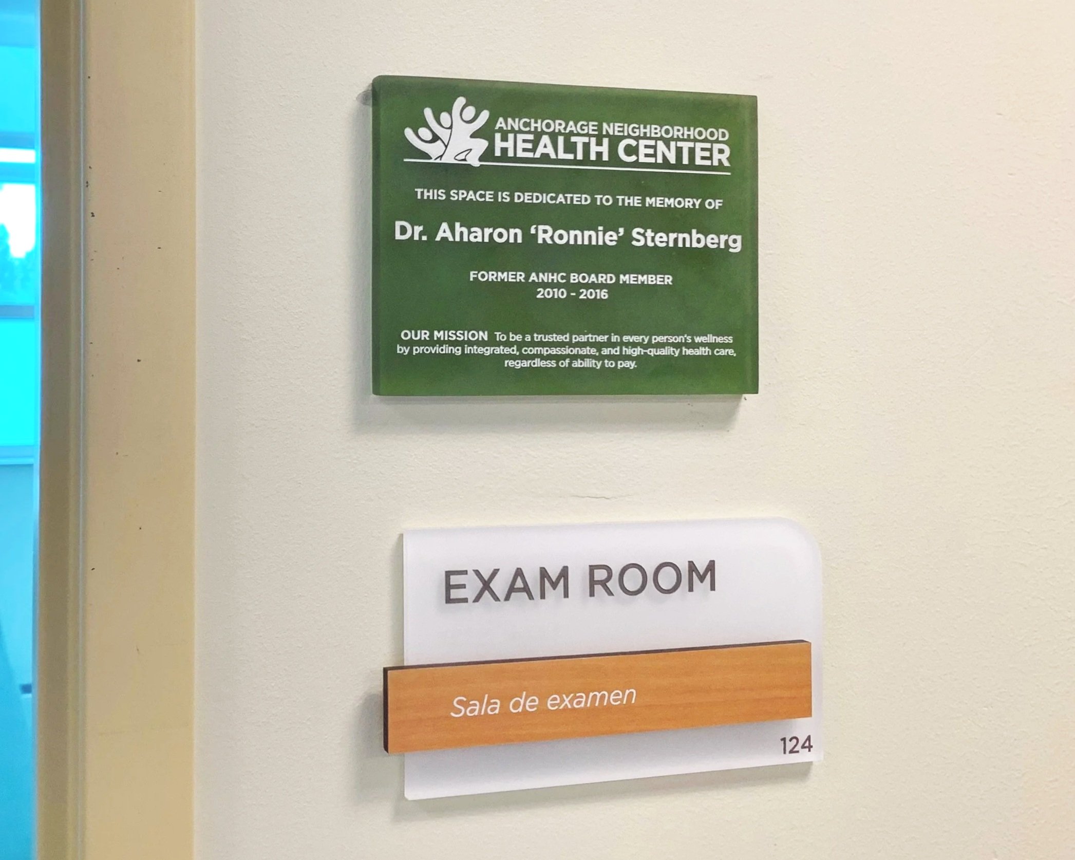 Wall plaque dedicating an exam room in memory of Dr. Aharon “Ronnie” Sternberg above an “Exam Room” sign.