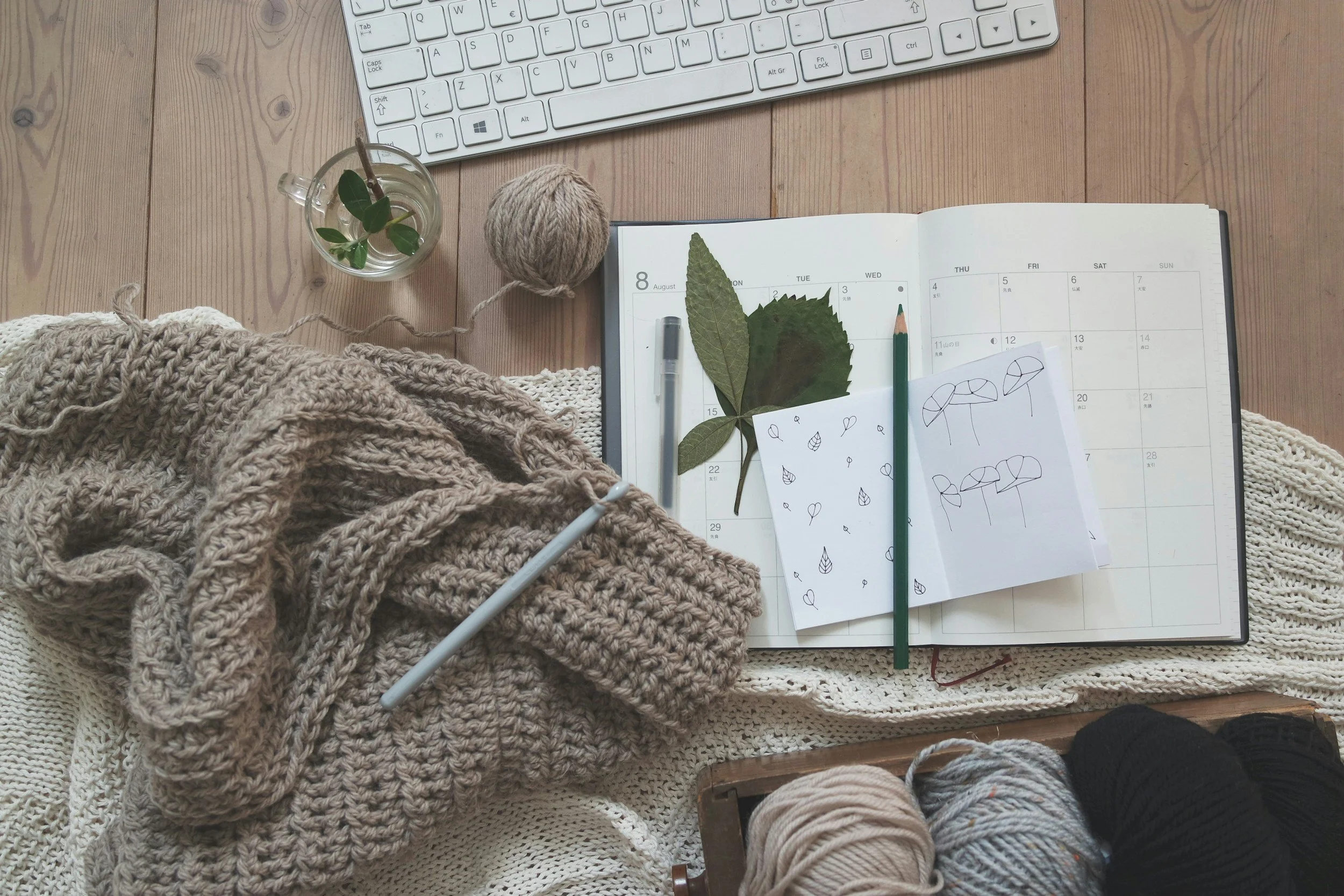 Cozy flat lay with planner, knitting, and natural elements, representing intentional living, self-care, and emotional healing routines