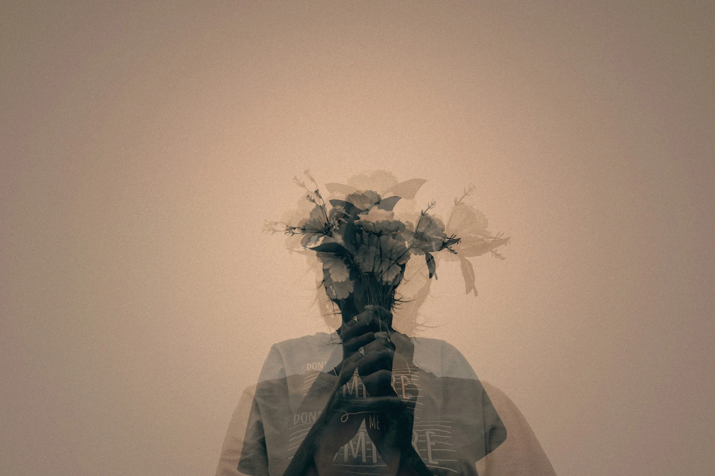 Double exposure image of person holding flowers over face, symbolizing emotional healing, identity, and inner growth in therapy