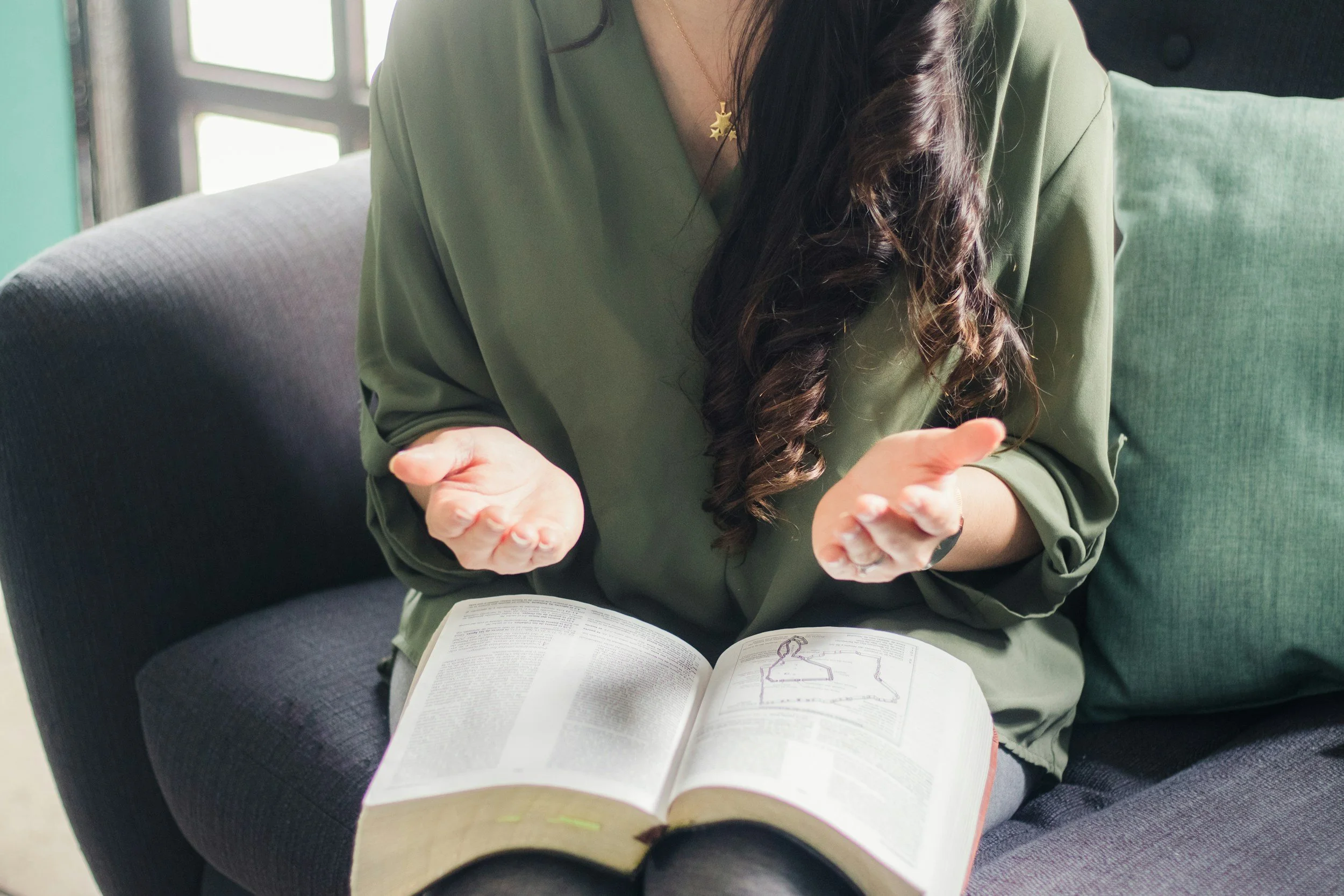 Woman reading Bible with open hands, representing prayer, faith, and emotional healing through faith-based therapy for anxiety