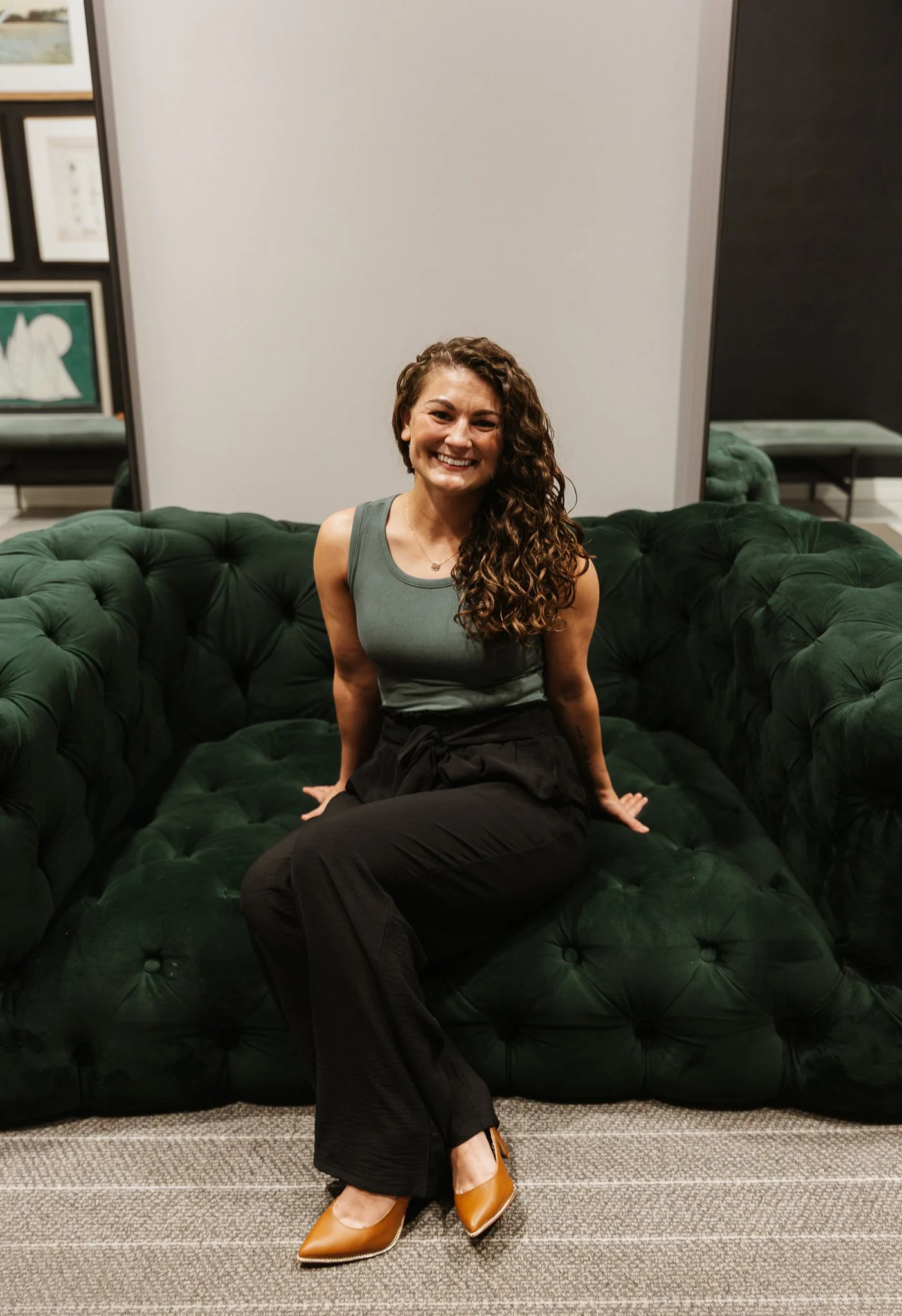 Therapist sitting on green couch in welcoming office space, offering support for anxiety, attachment wounds, and relationship healing in Michigan