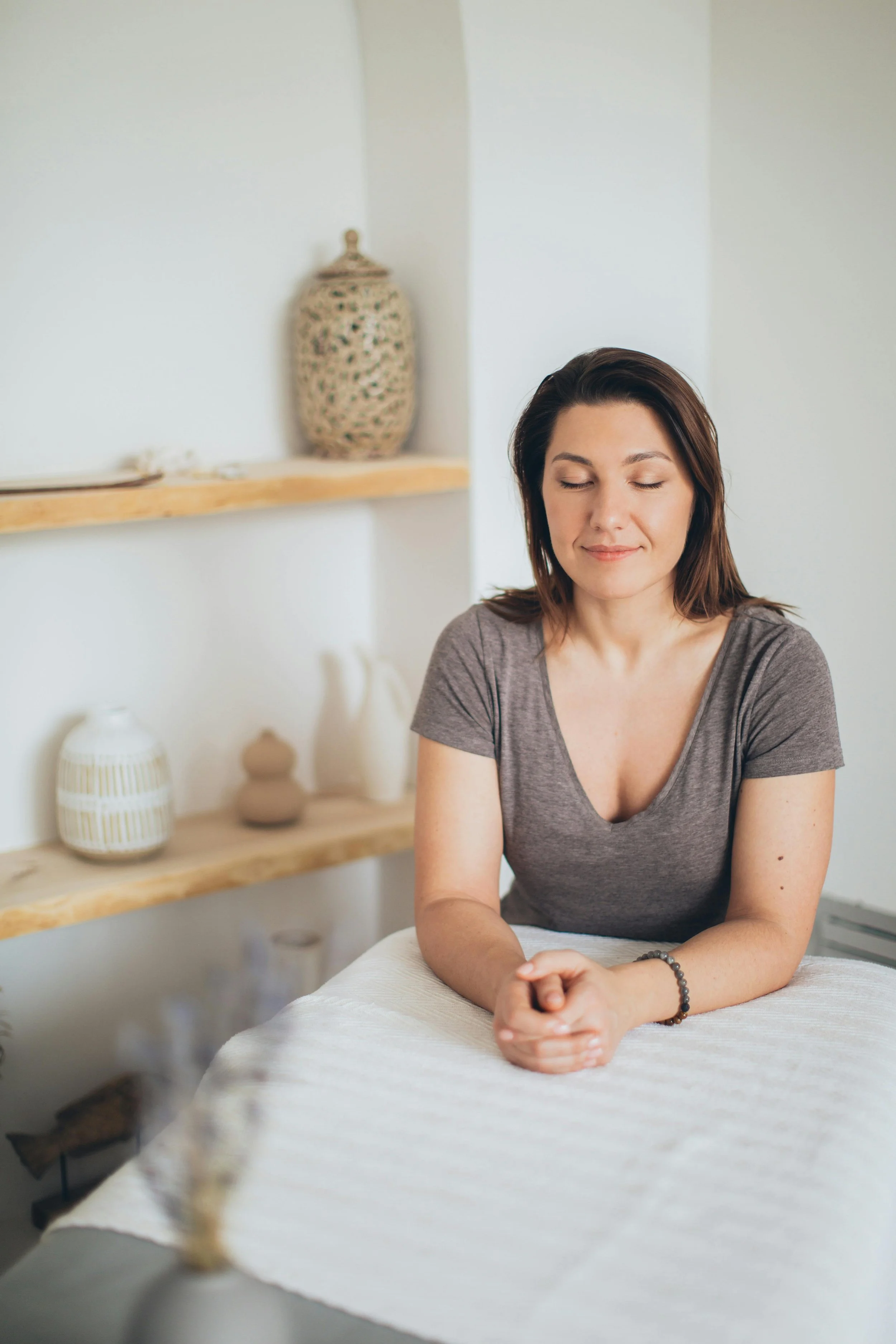 Woman sitting with eyes closed in peaceful space, representing mindfulness, grounding, and nervous system regulation in therapy