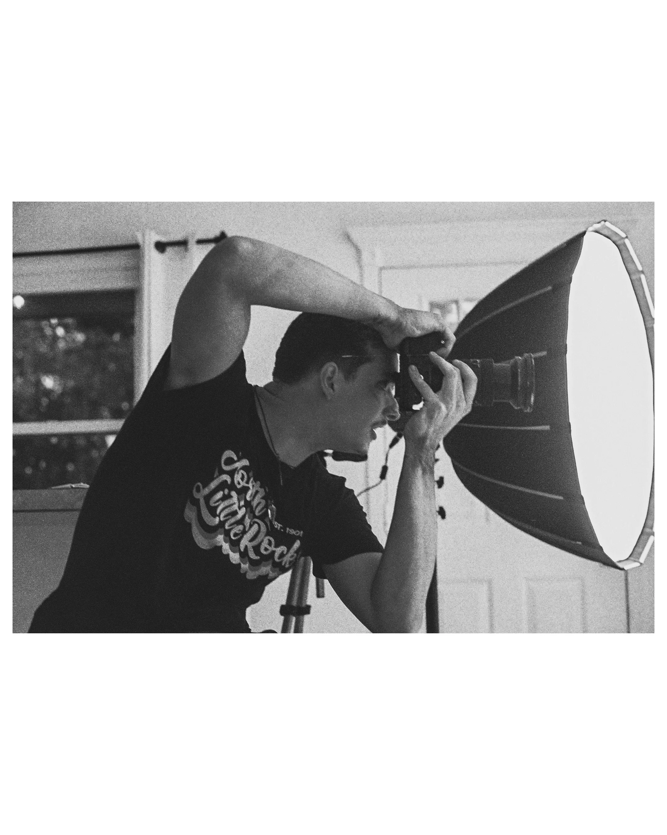 A man taking a photograph indoors using a camera with a large flash umbrella.