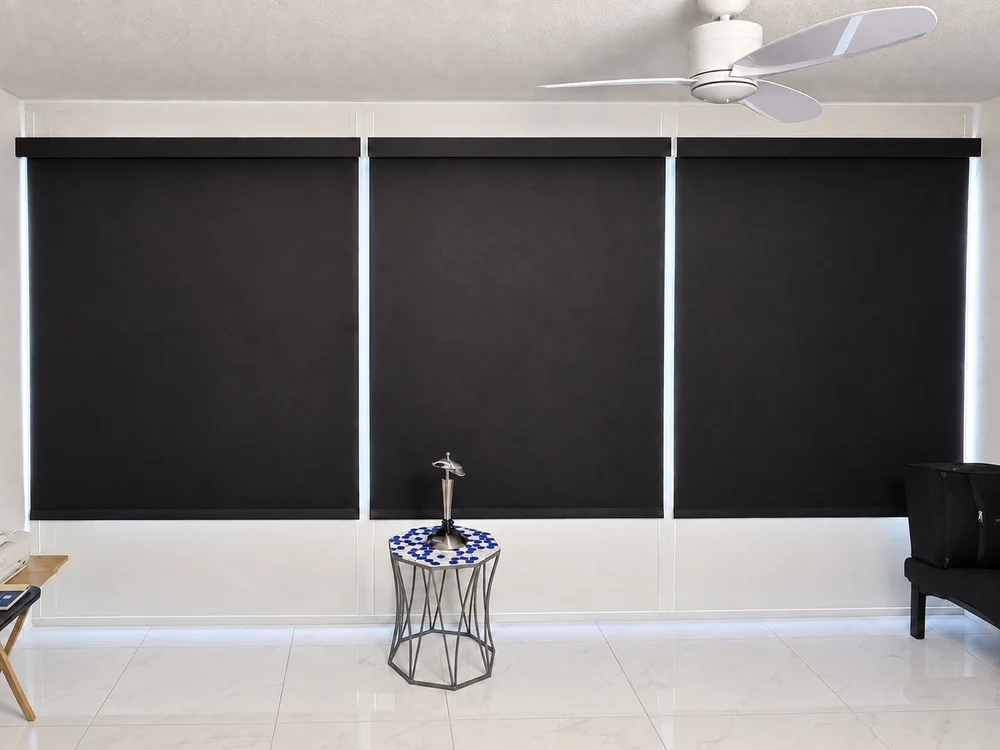Three dark roller shades fitted across a wide bank of windows