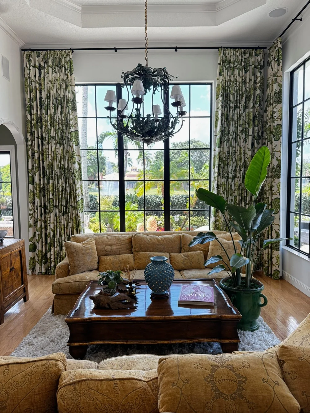 Botanical patterned drapery panels framing tall black-framed living-room windows