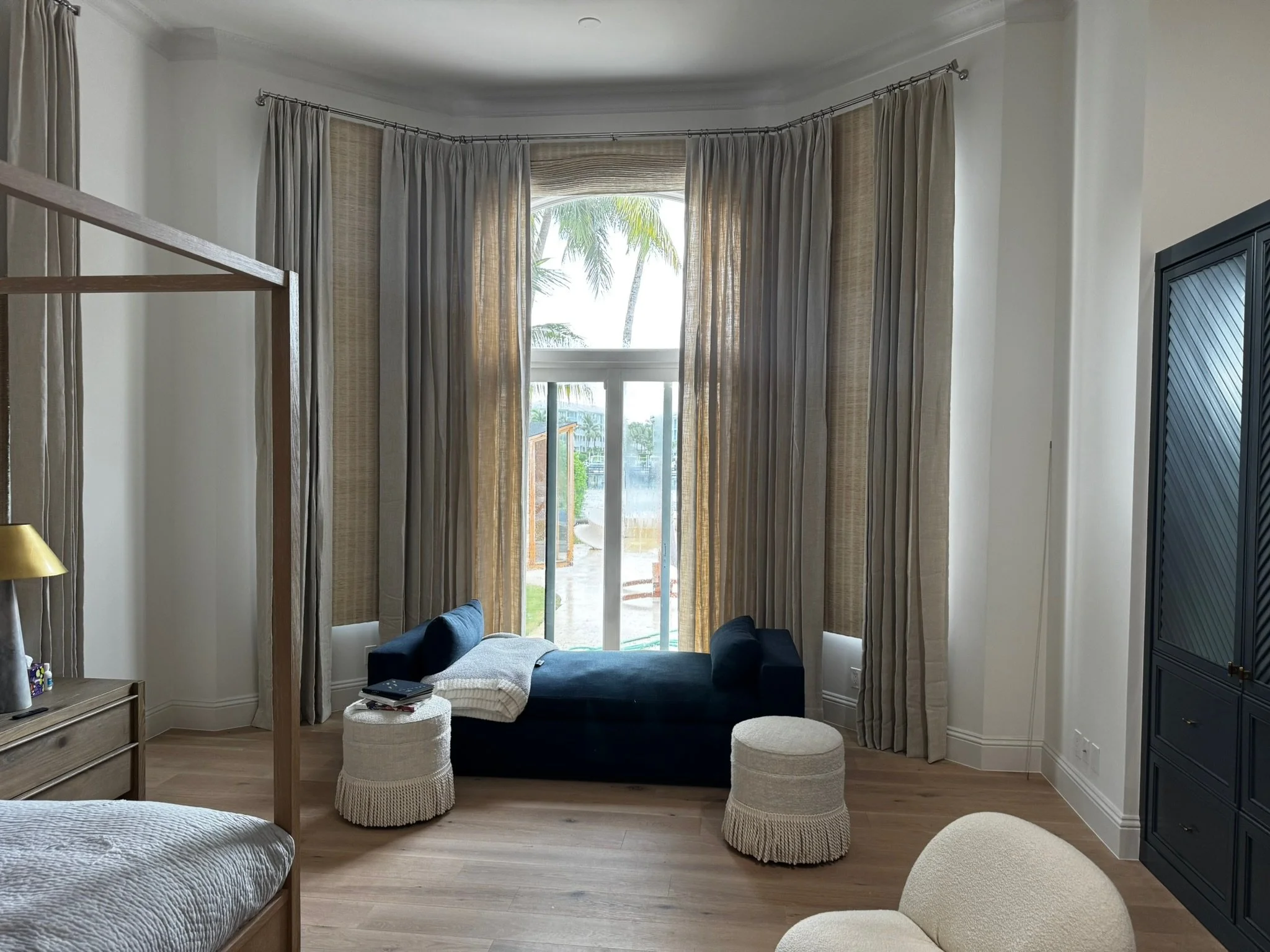 Neutral custom drapery layered with woven shades in a South Florida bedroom
