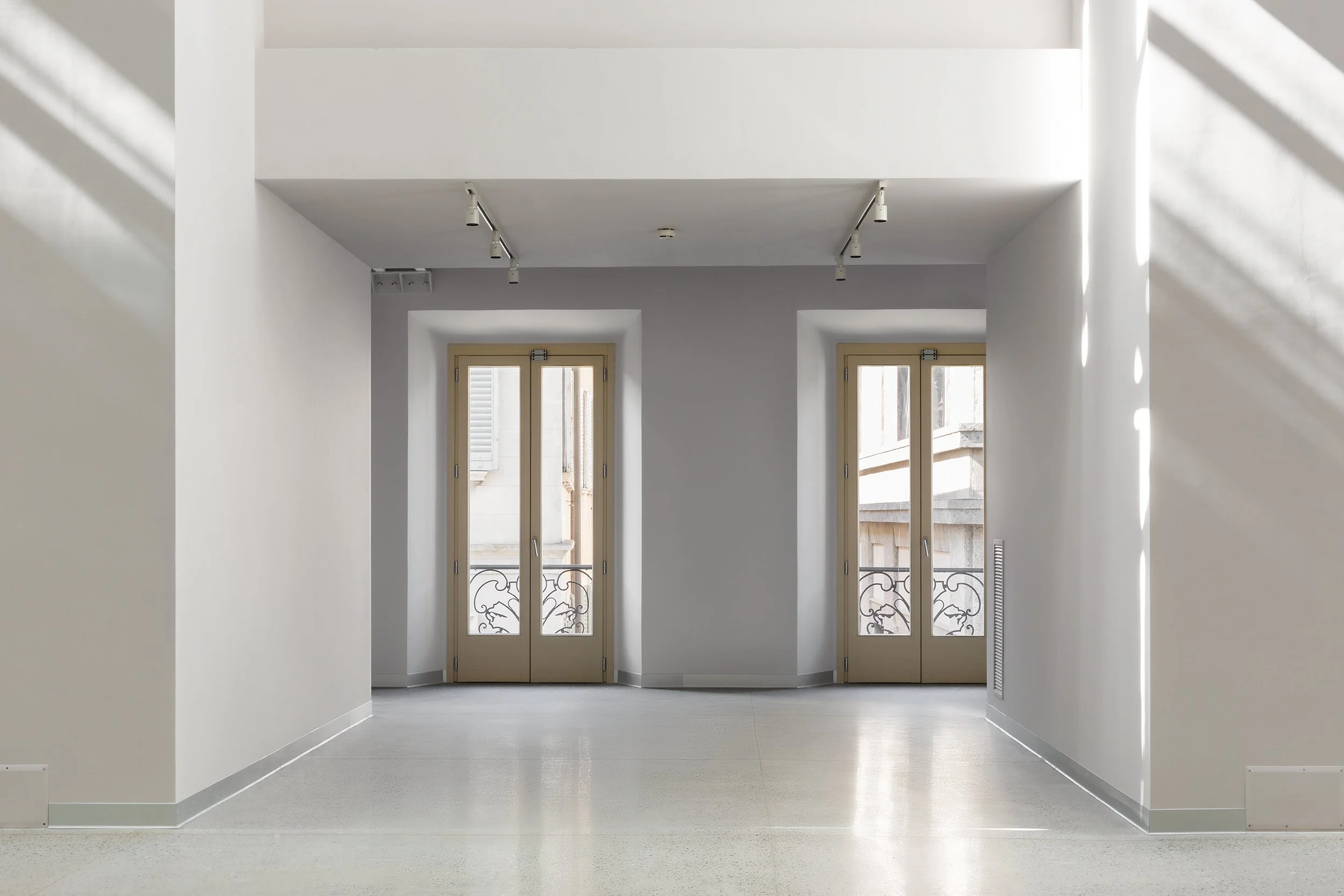 Renovated interior space of Palazzo Citterio in Milan, part of the Grande Brera project, featuring minimalist architectural design, restored windows, terrazzo flooring, and soft natural light.