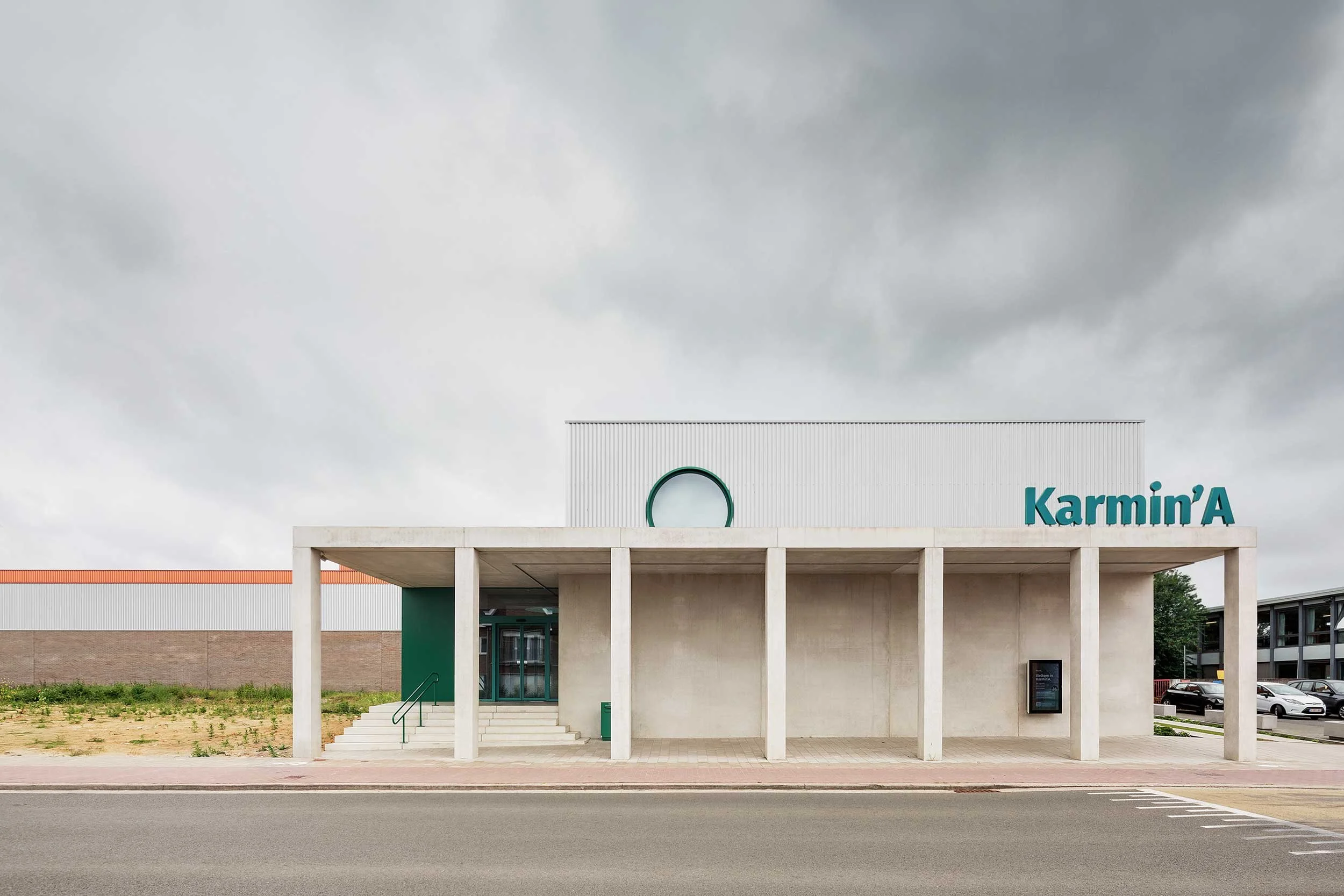 photo of the facade in concrete and metal of the new building in Aalter, under a cloudy sky