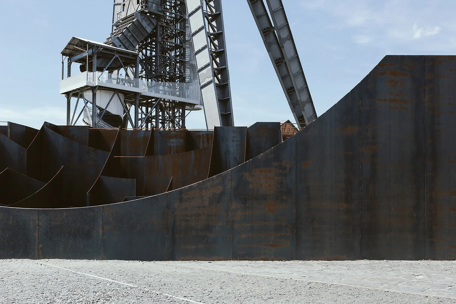 Contemporary steel architecture at a historic coal mine redevelopment site in Genk, Belgium. This image captures the interaction between rusted steel surfaces and preserved industrial structures.