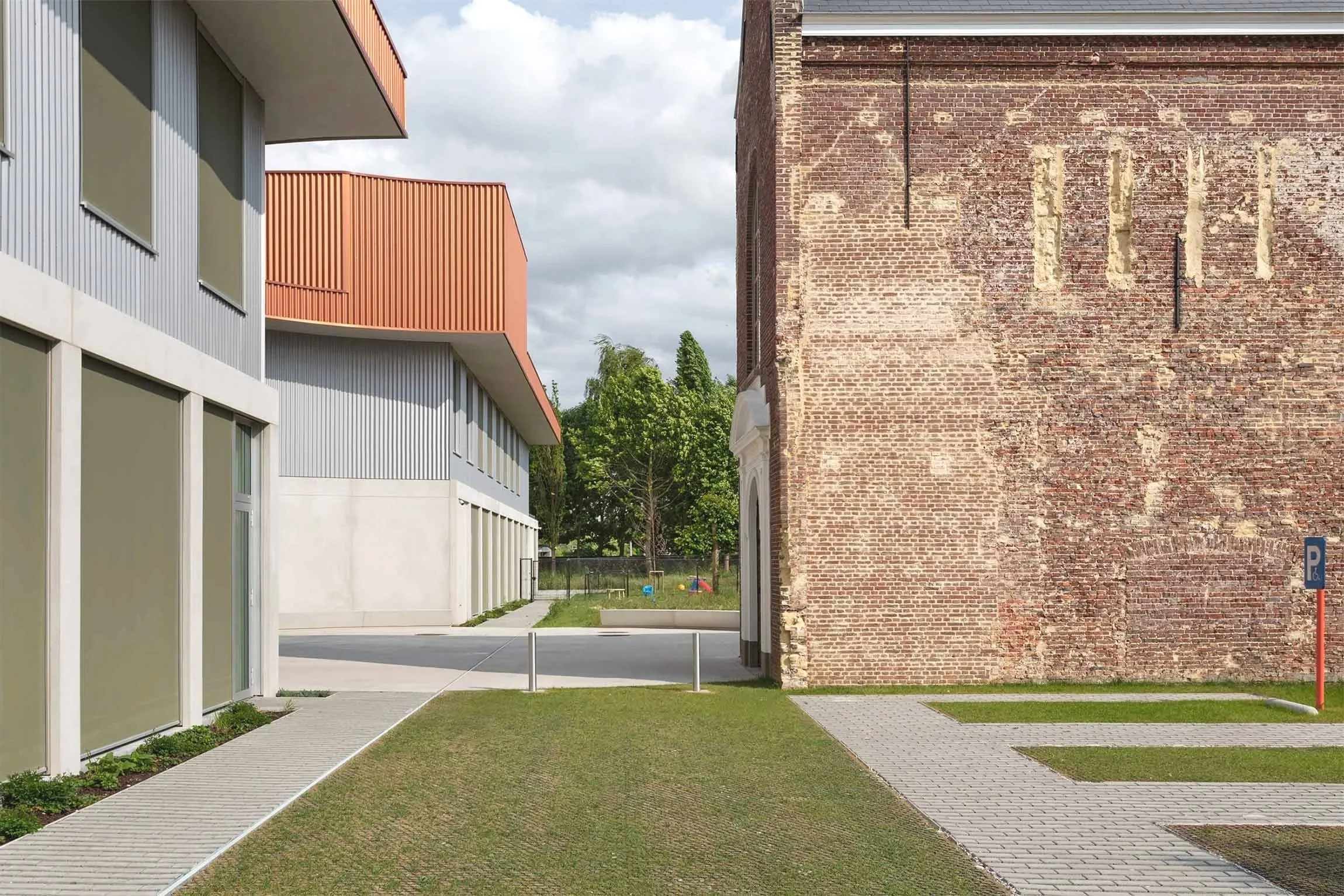 Exterior view of the project Karmin’A multifunctional center in Knesselare, showing the design that combines the restoration of existing elements, like the historic convent chapel, with new volumes and the with bicycle parking.