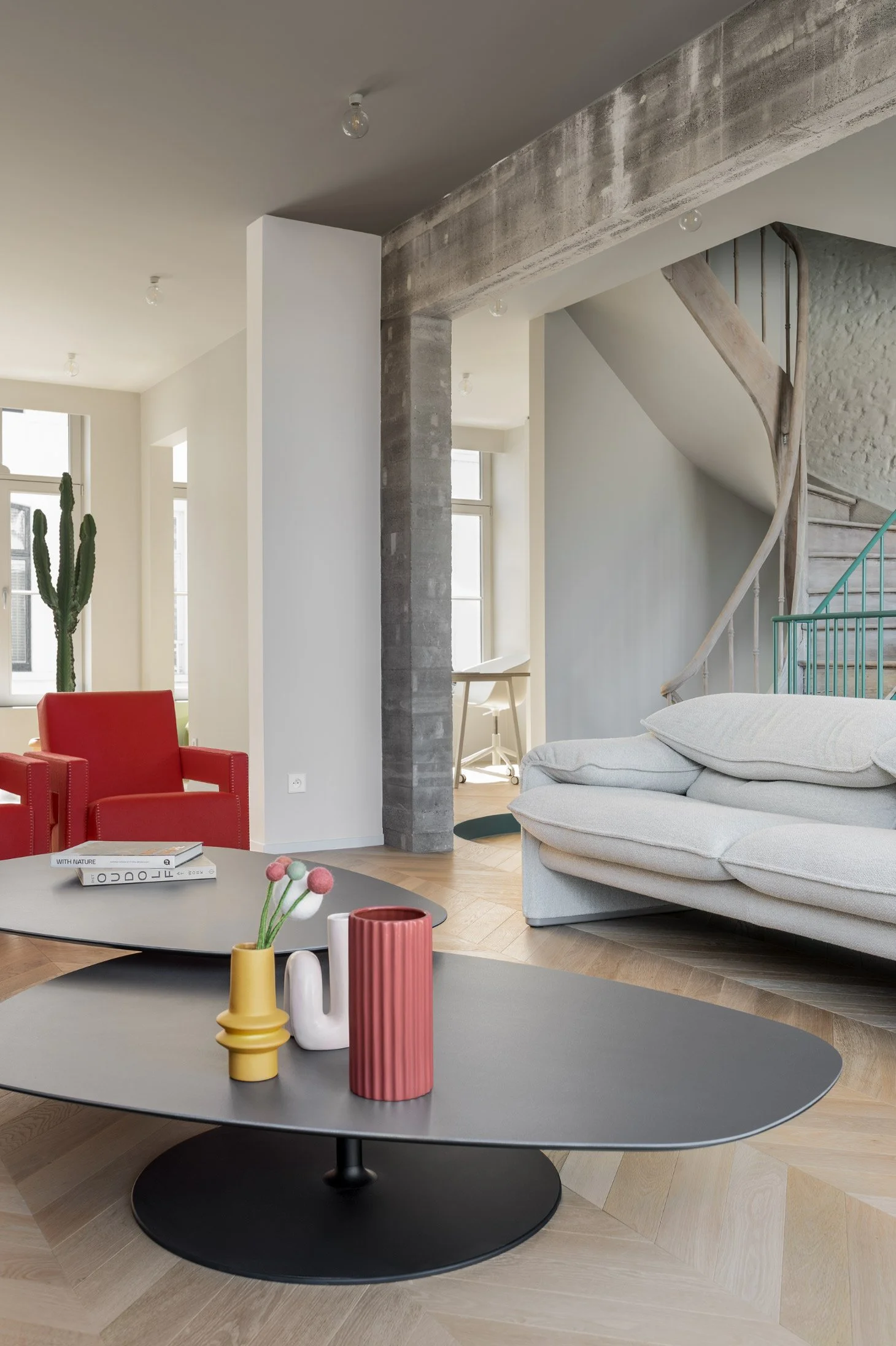Interior view of a renovated house that combines modern design with historical character. The living area features a Cassina Maralunga sofa, two red Utrecht armchairs by Cassina and a Moroso Phoenix table.