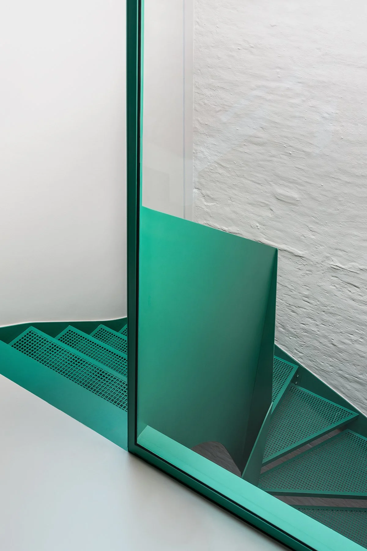 Detail of a minimal interior staircase in green perforated metal adjacent to the bathroom, part of a townhouse renovation in Bruges