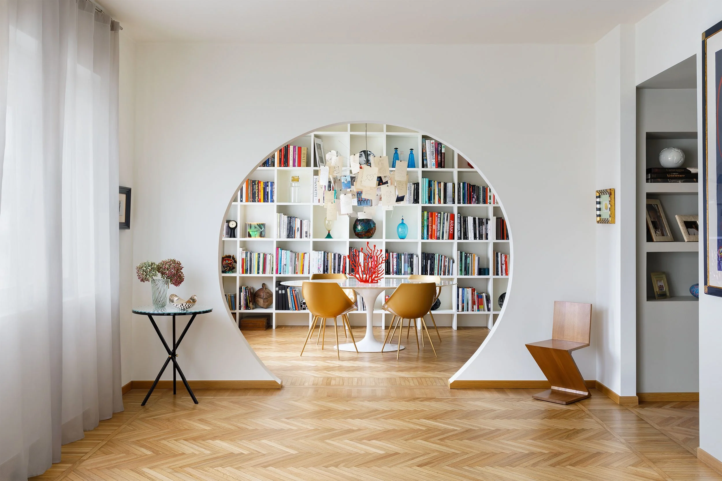 Interno residenziale a Milano dove lo spazio living è definito da una libreria su misura a tutta parete inserita in una scenografica nicchia circolare