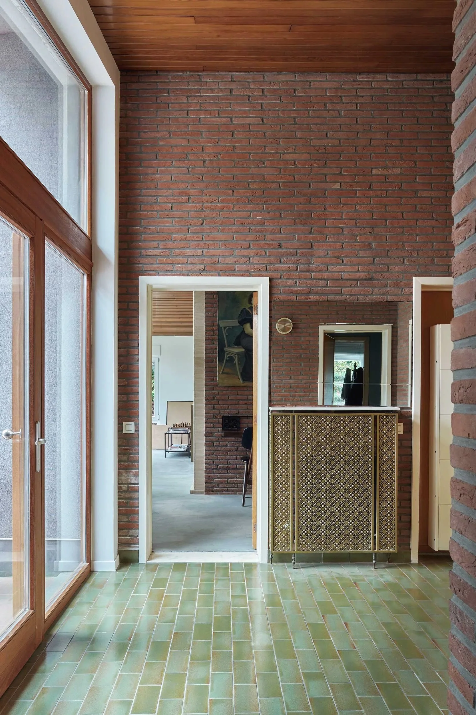 Interior of a vintage 70s home with green ceramic tiles, brick wall finishes, wooden doors, and integrated cabinetry.
