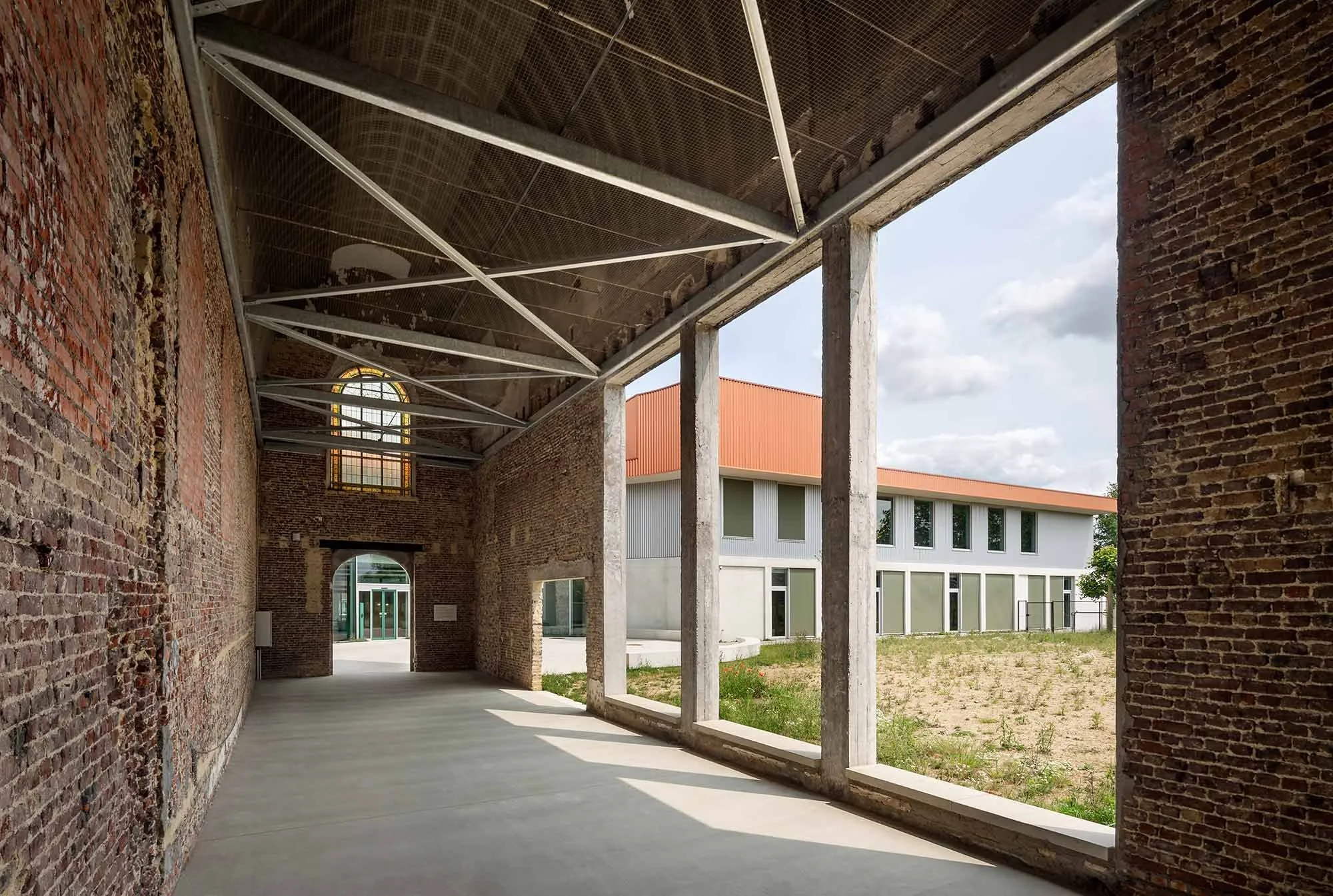 The photo shows a view from inside the old monastery in bricks, where the new part of the building can be seen through the large windows.
