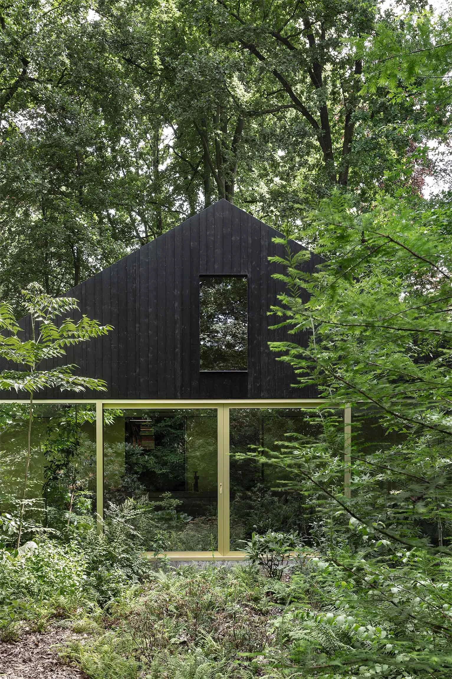 Golden anodized facade with wooden cladding on the modernized holiday home in the woods by basil architecture