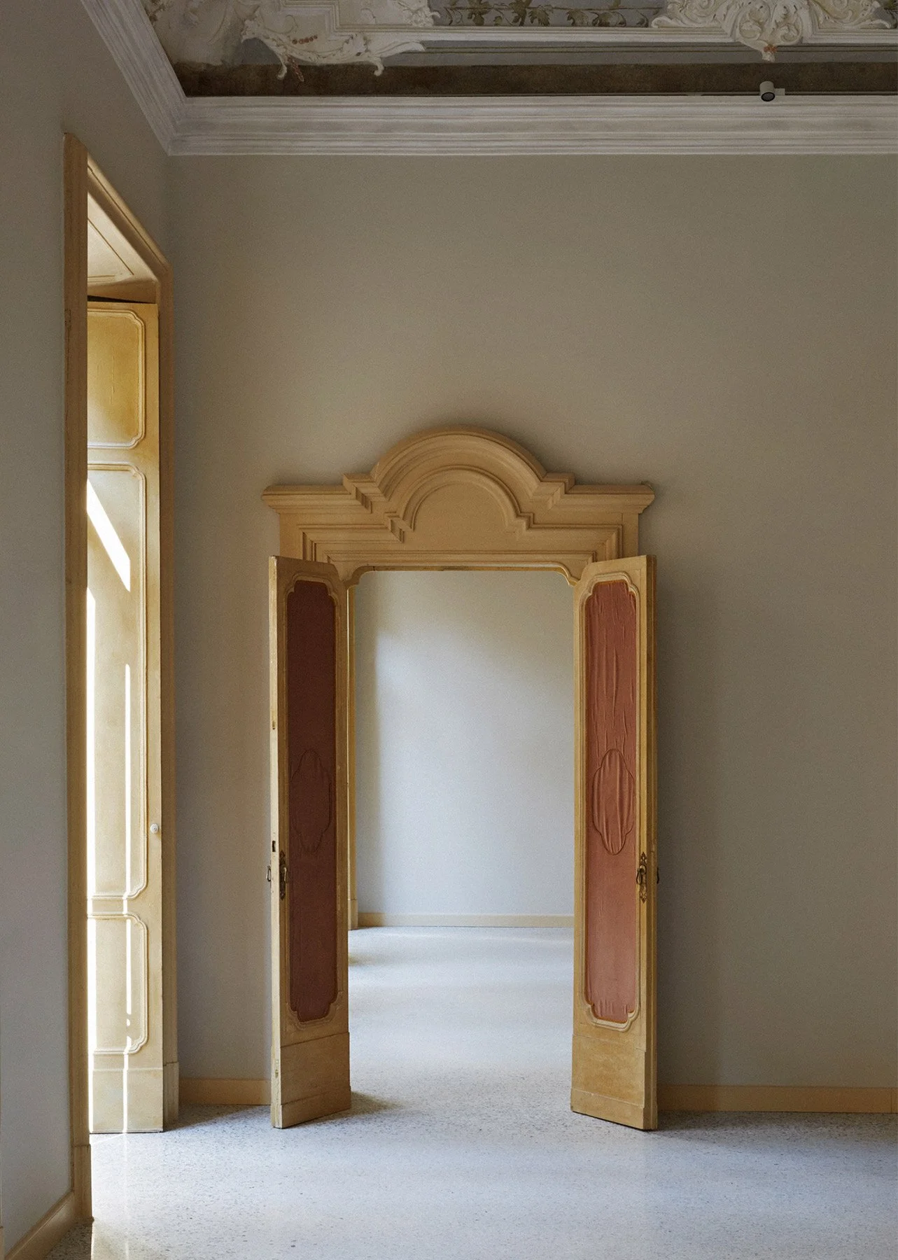 Interno di Palazzo Citterio a Milano, photo of an 18th-century Baroque-style door, con porte storiche restaurate in tonalità oro e terracotta, soffitti decorati in stucco e pavimento in seminato alla veneziana.