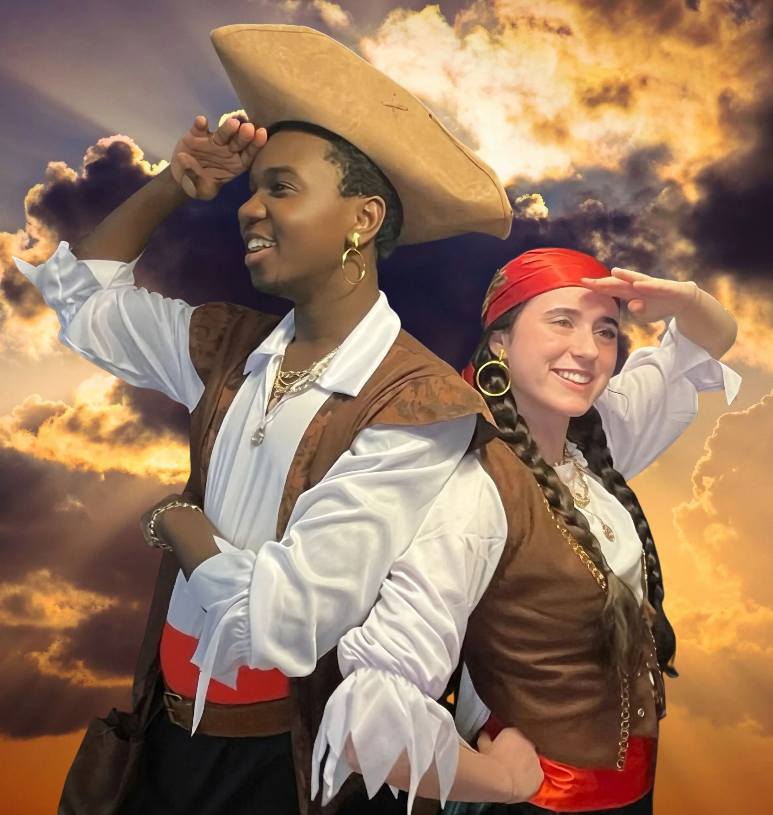 Two women in traditional costumes saluting against a dramatic sunset sky with clouds, one with a wide-brimmed hat and jewelry, the other with a red headscarf and red shorts.