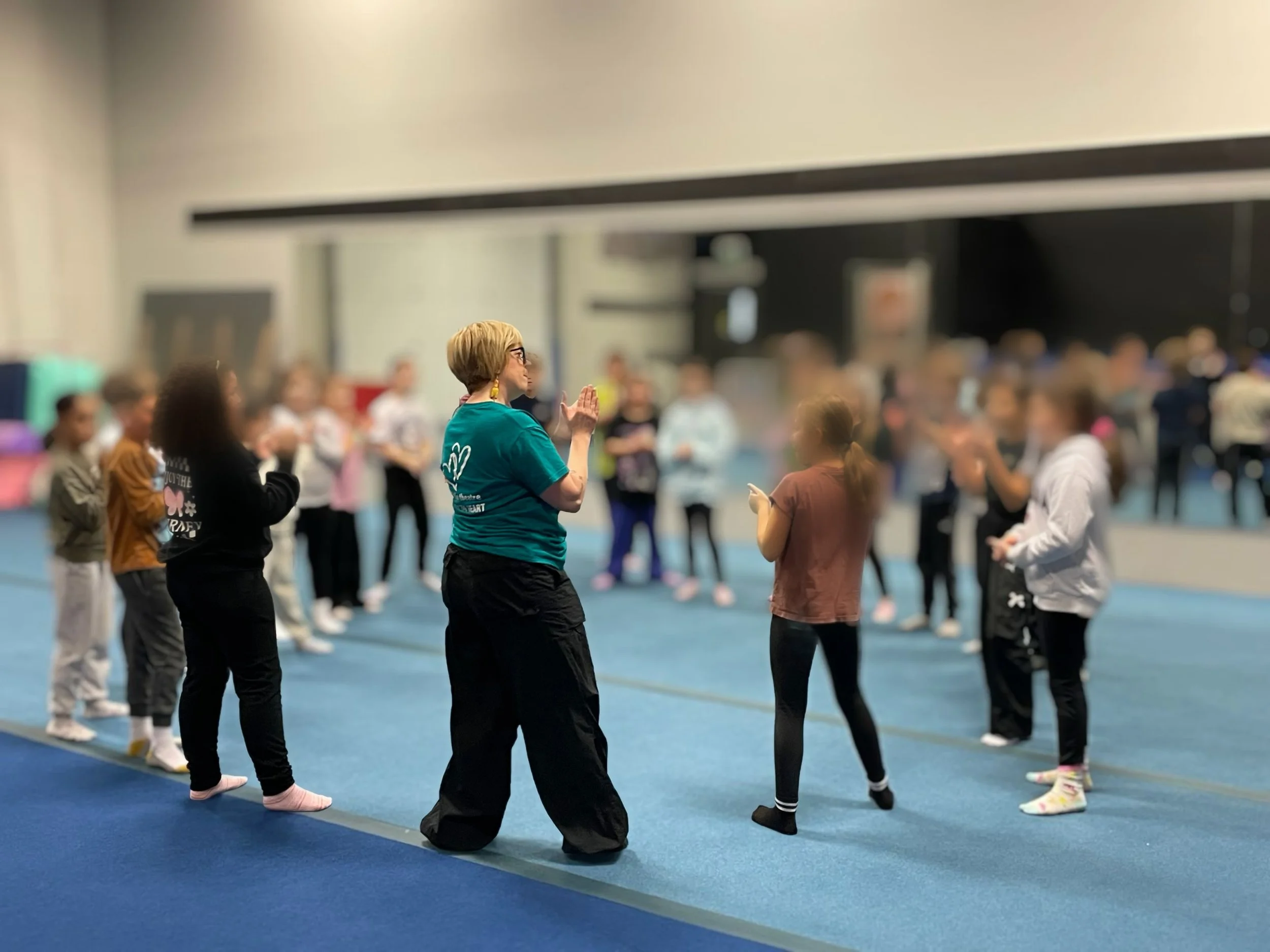A group of children enjoy theatre class at Big Hearts Little Theatre's Stage Quest workshop, guided by an adult instructor, Erin Newton.