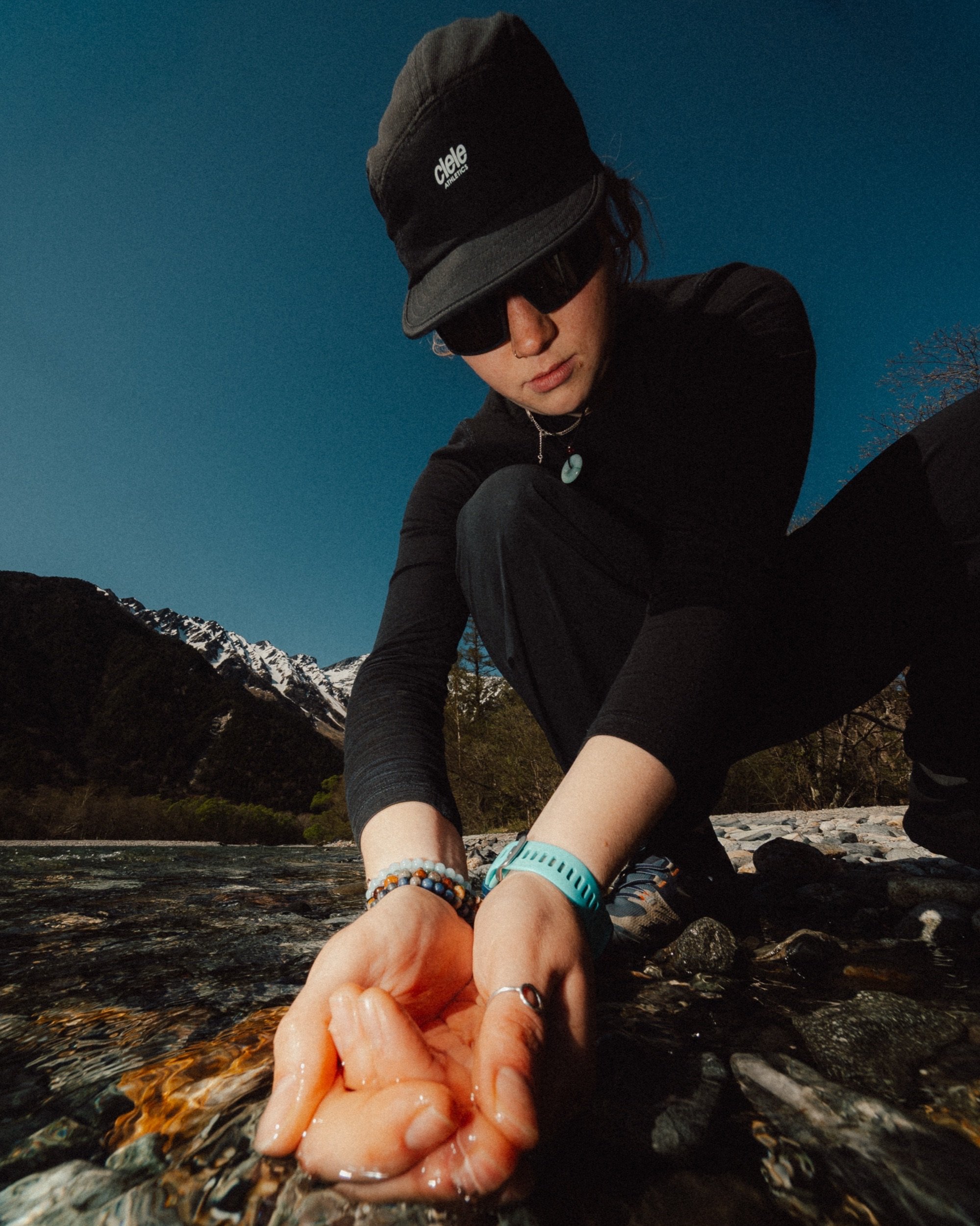 Hiker in a Ciele cap refilling water on the trail in Kamikōchi, Japan. Flash photography close up fisheye.