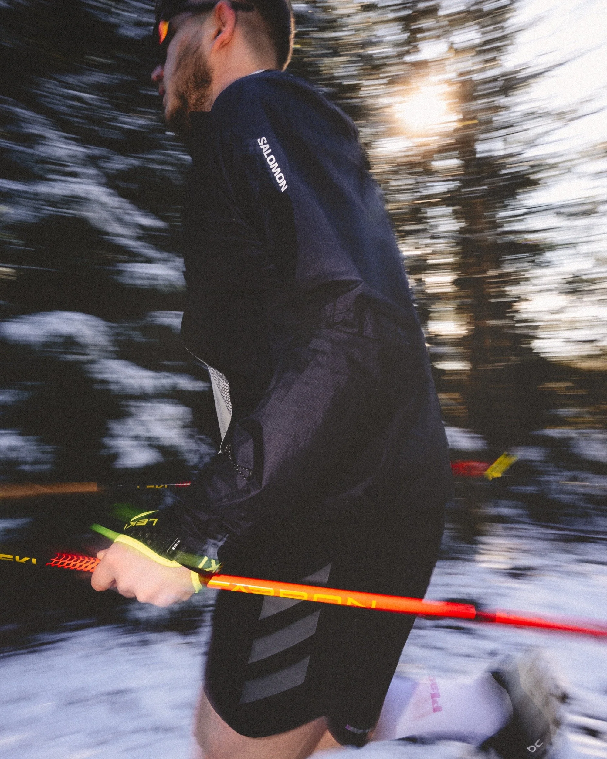 Snowy Trail runner in Salomon Jacket with poles at sunset