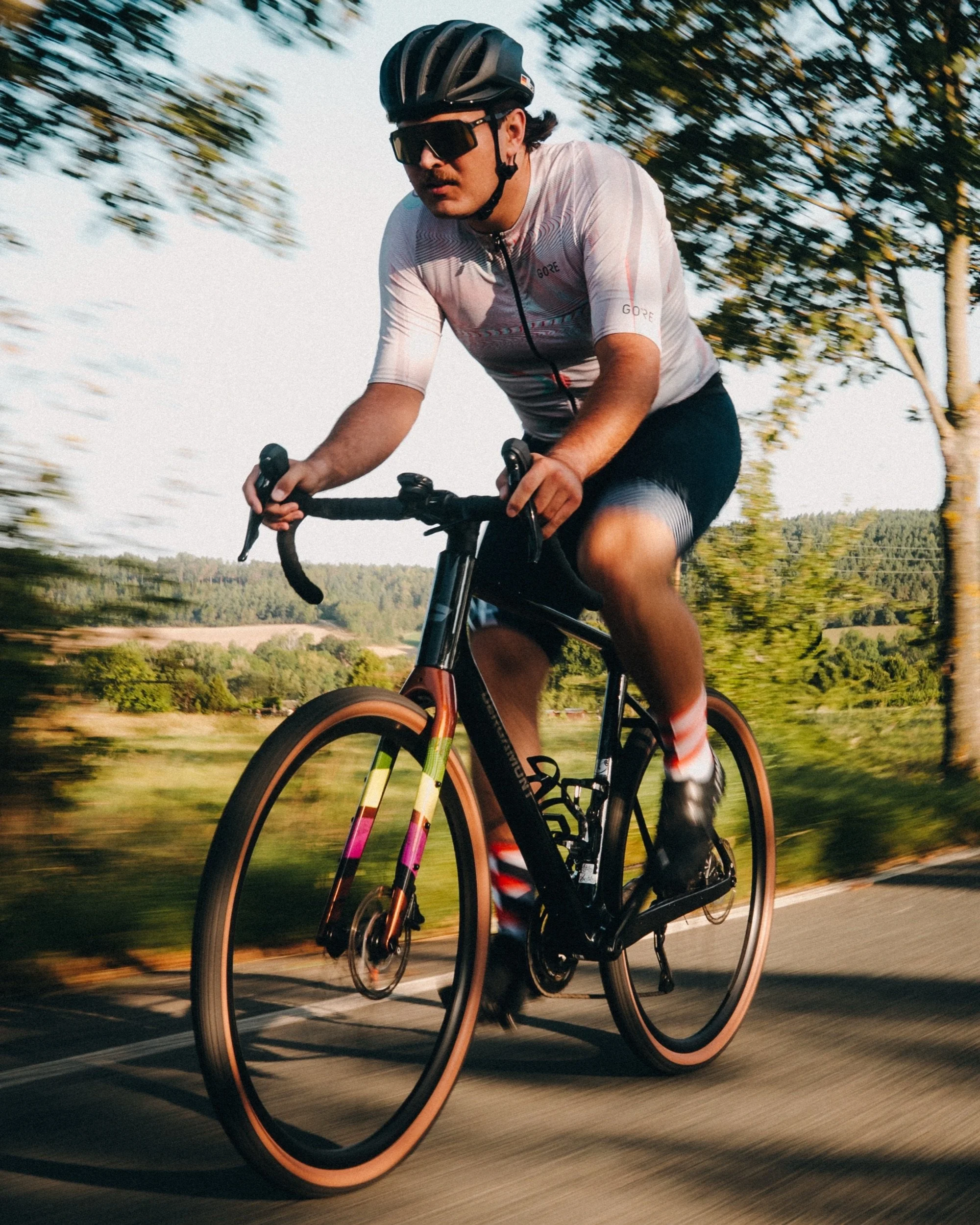 Road cyclist in motion with trees in the background