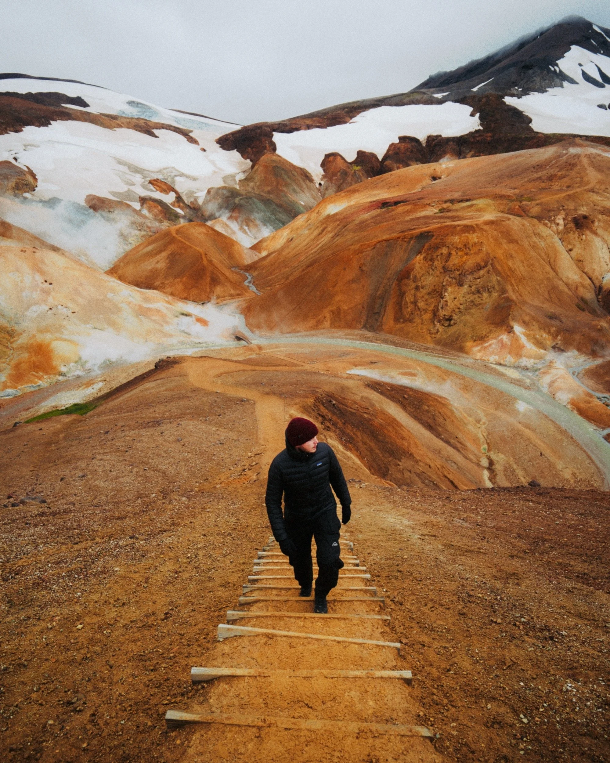 Hiker on a wooden staircase through rhyolite mountains, Icelandic Highlands