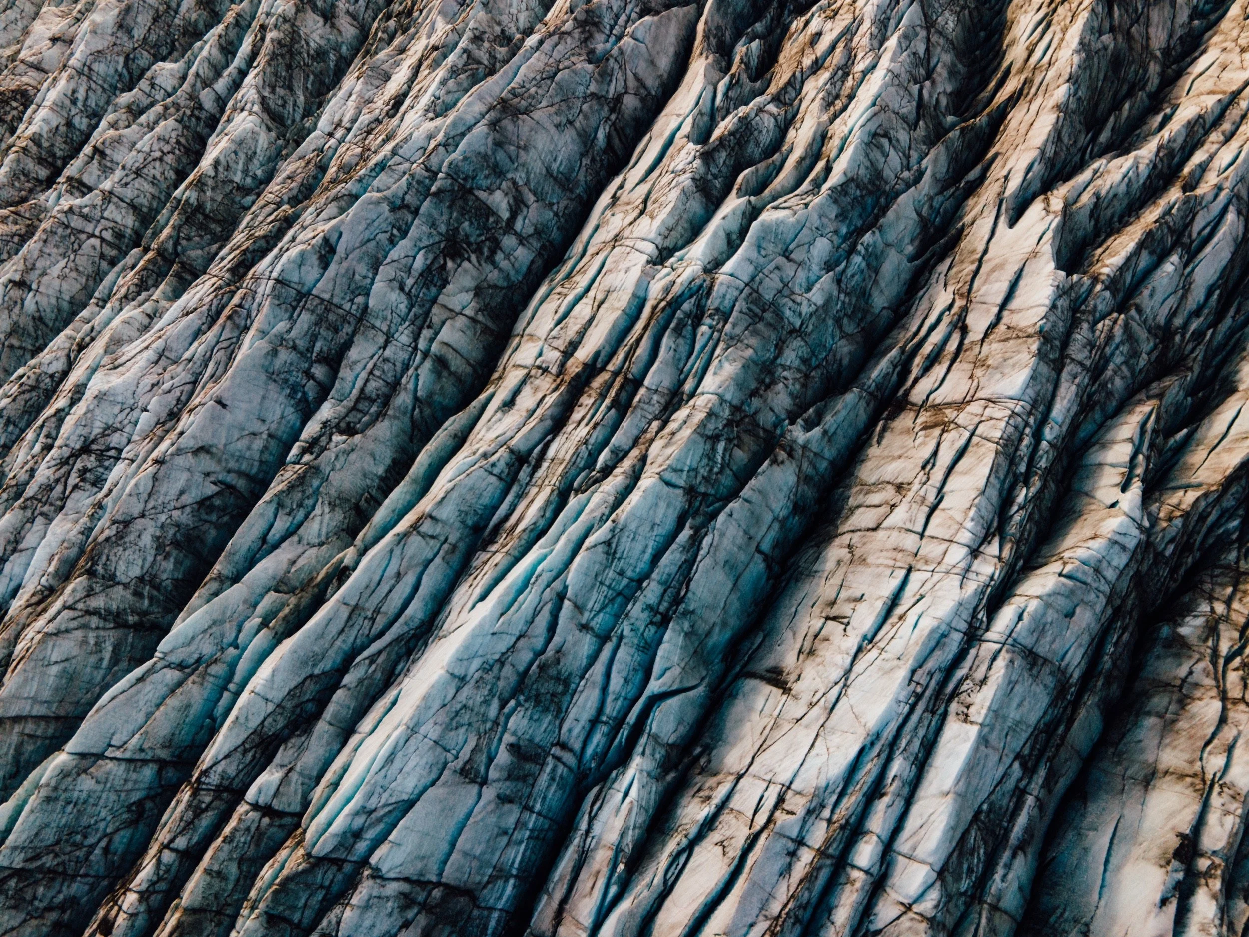 Aerial close-up of glacier ice with ash layers and crevasses, Iceland