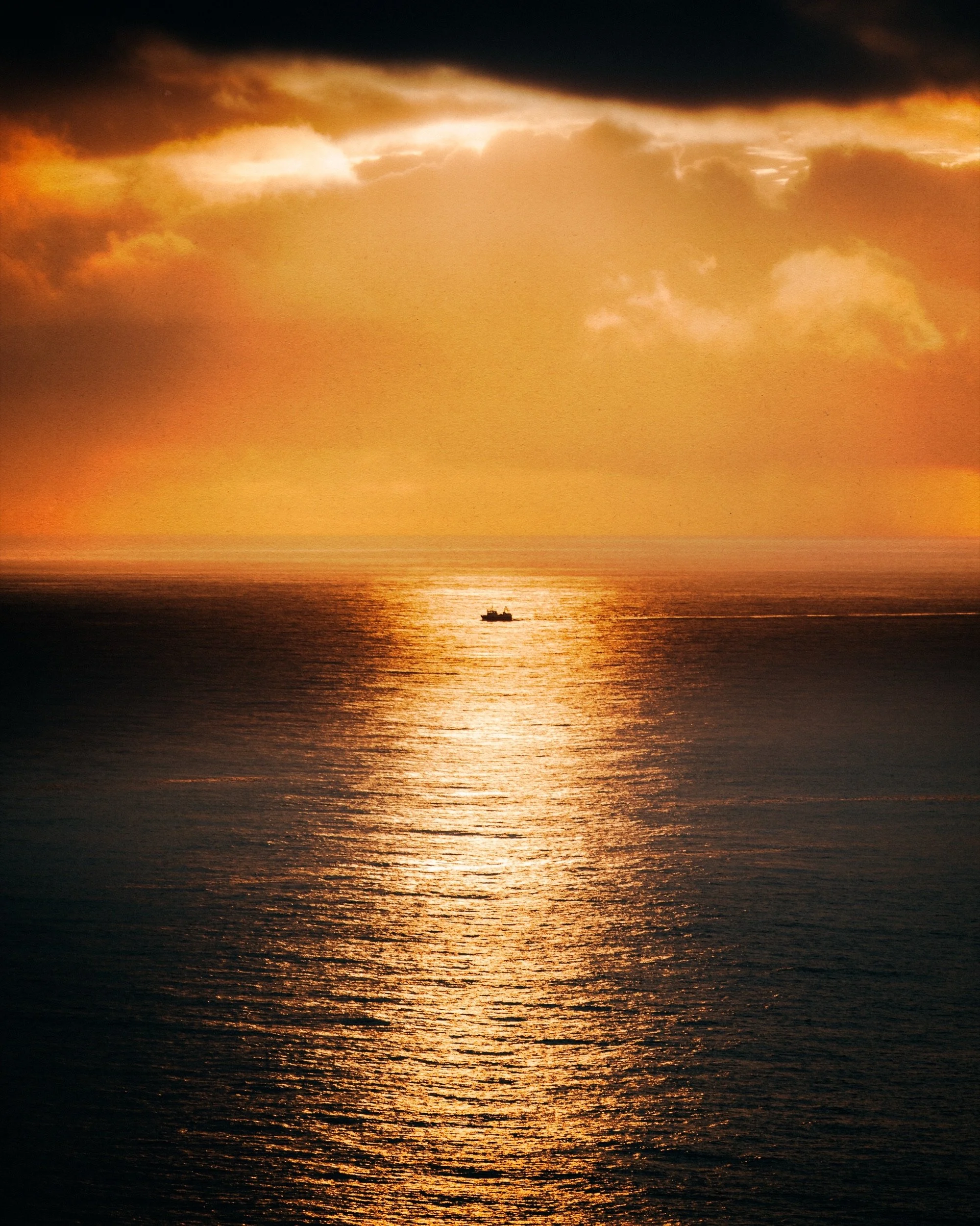 Boat on the ocean at sunset, golden light off the coast of Iceland