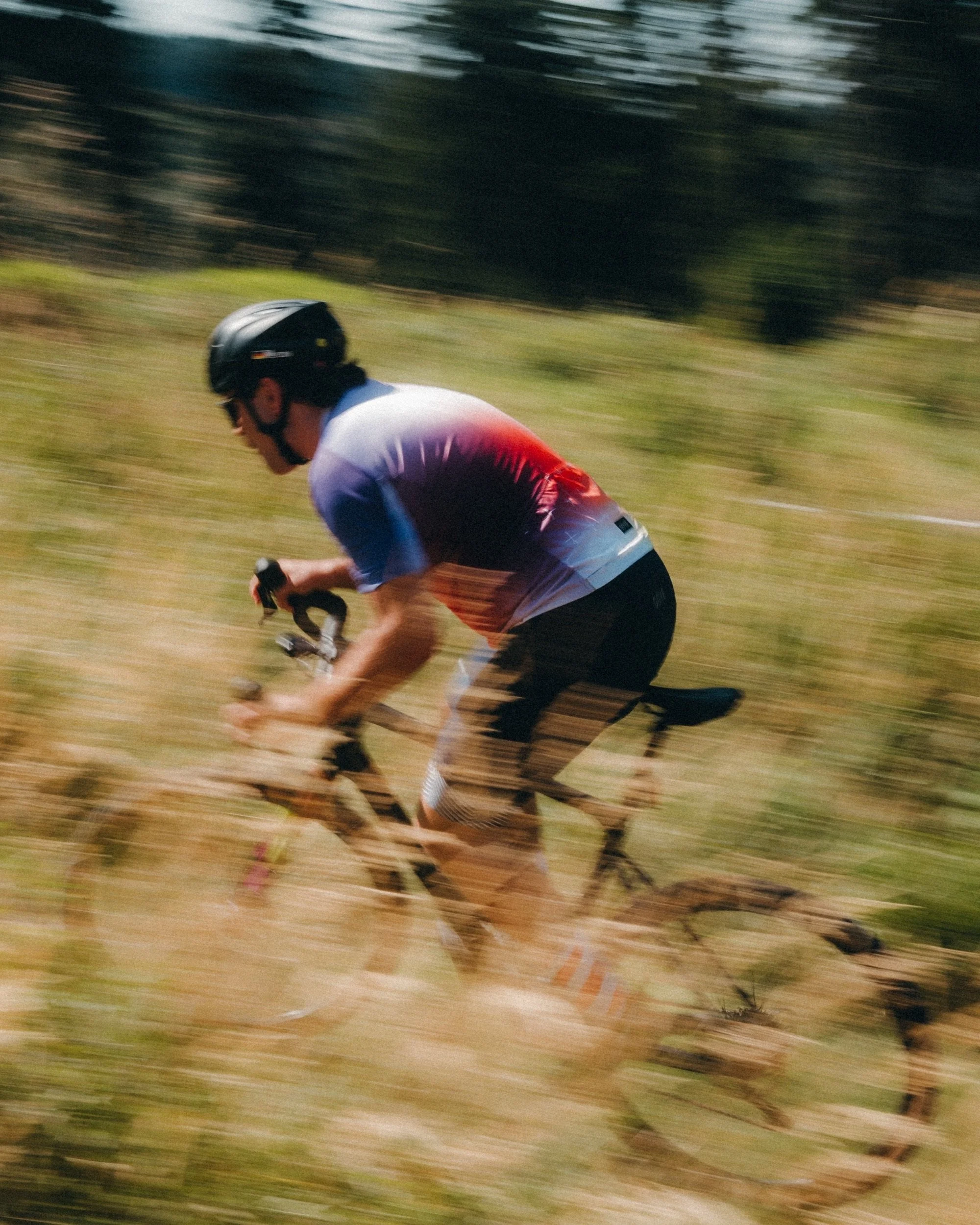Gravel cyclist racing across a field, motion blur. Thuringian Forest, Germany.