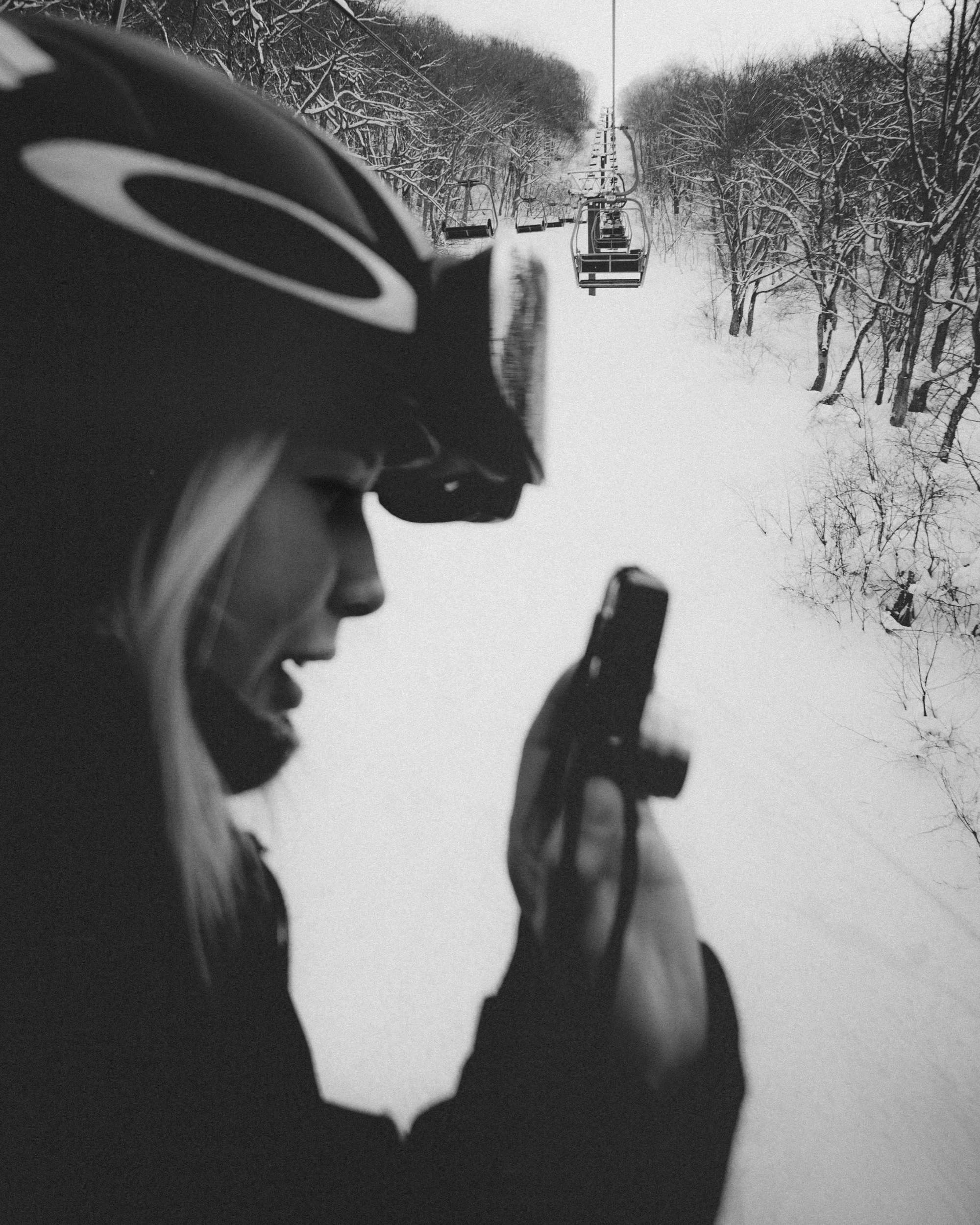 Skier taking a photo between snow-covered trees and a ski lift, Tangram, Japan