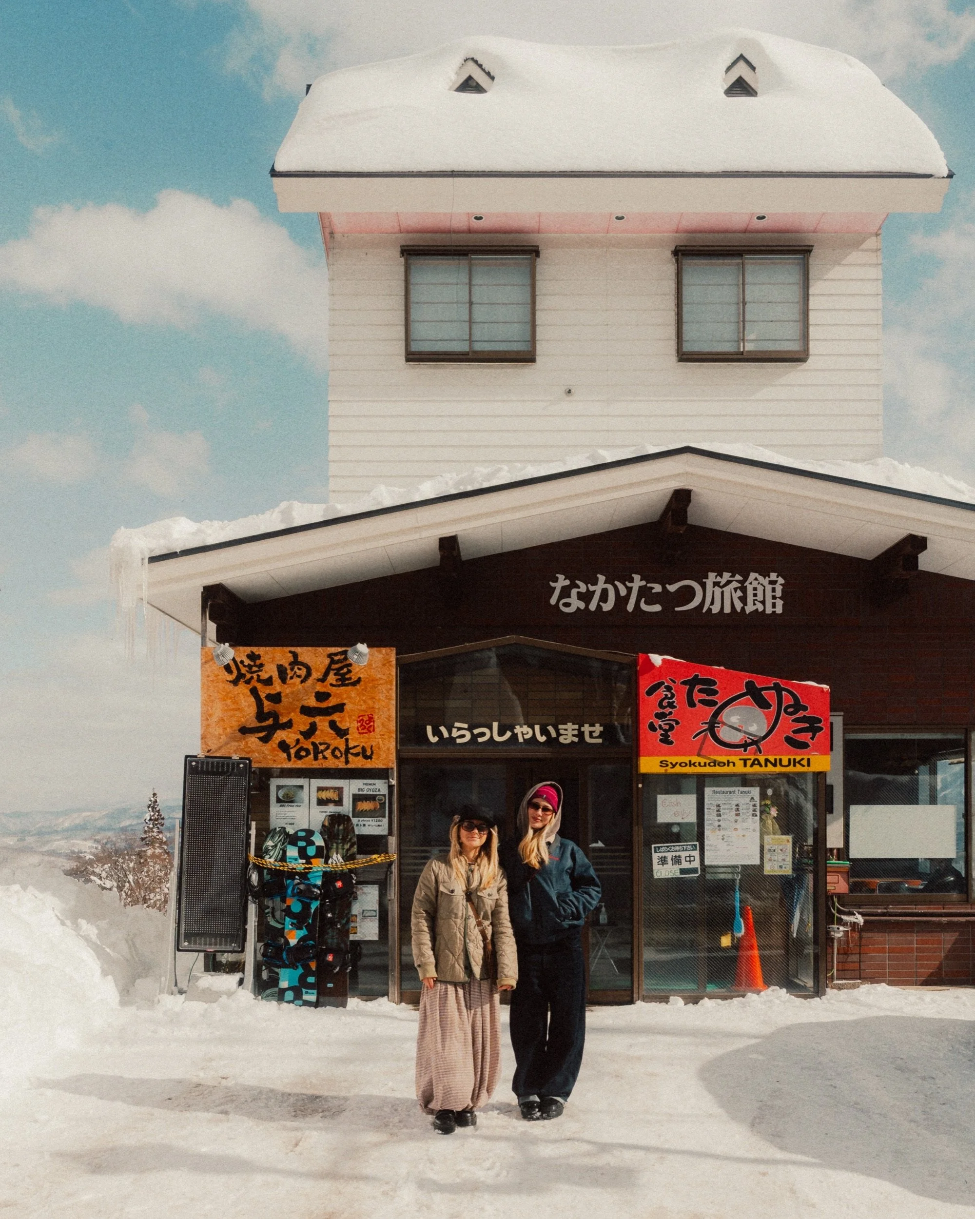 Two women in front of a snow-covered house in Myoko Onsen, Japan