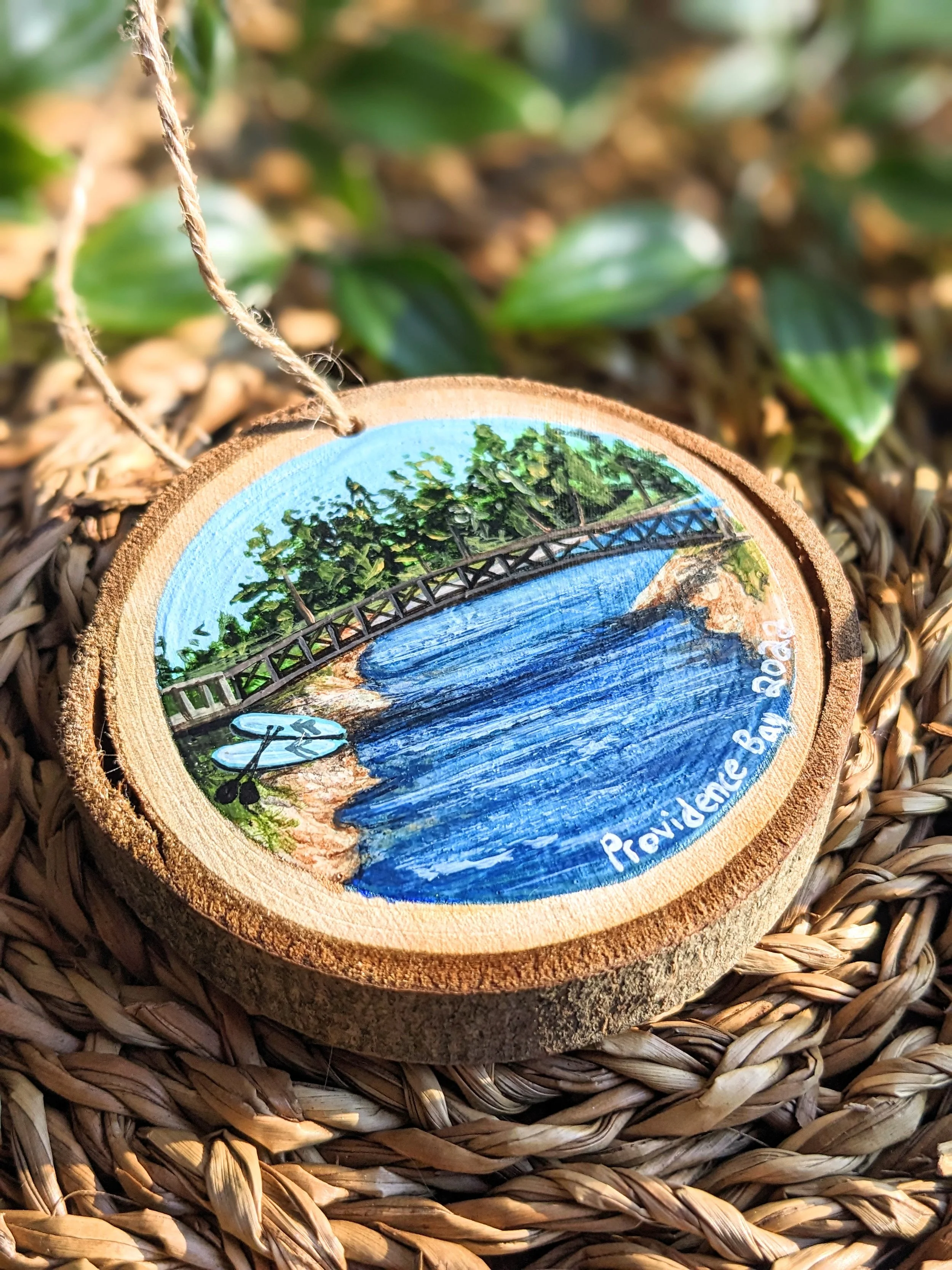Custom hand-painted Christmas ornament featuring paddle boards under the bridge at Providence Bay Manitoutlin Island (2022)