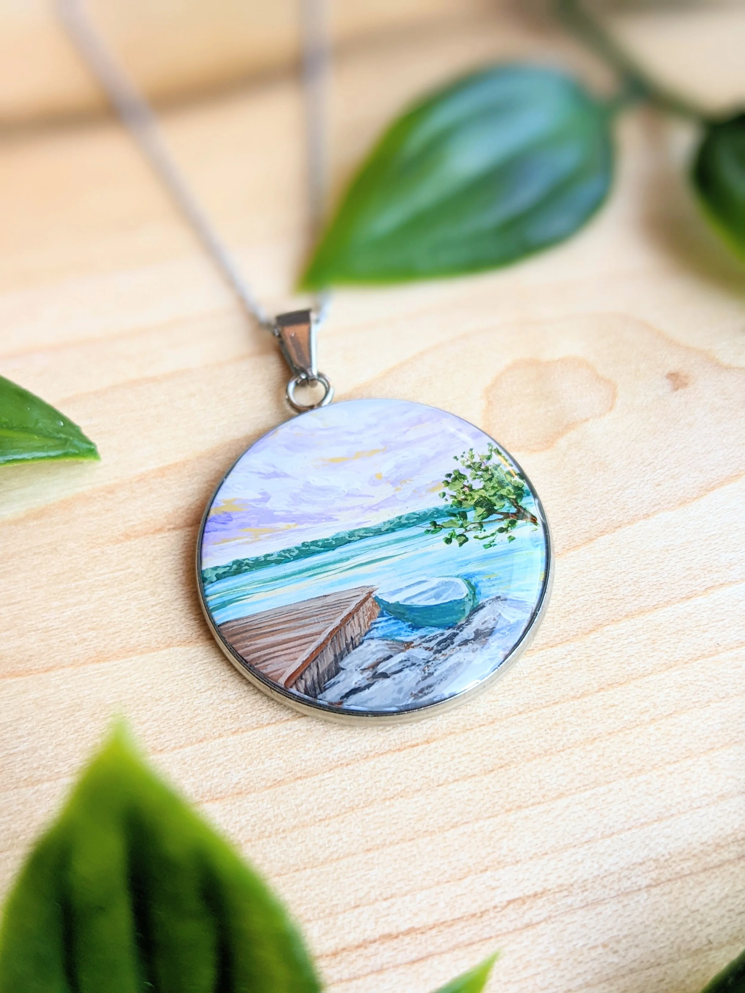 Custom hand-painted necklace featuring a lakeside dock and fishing boat at sunset (2022)