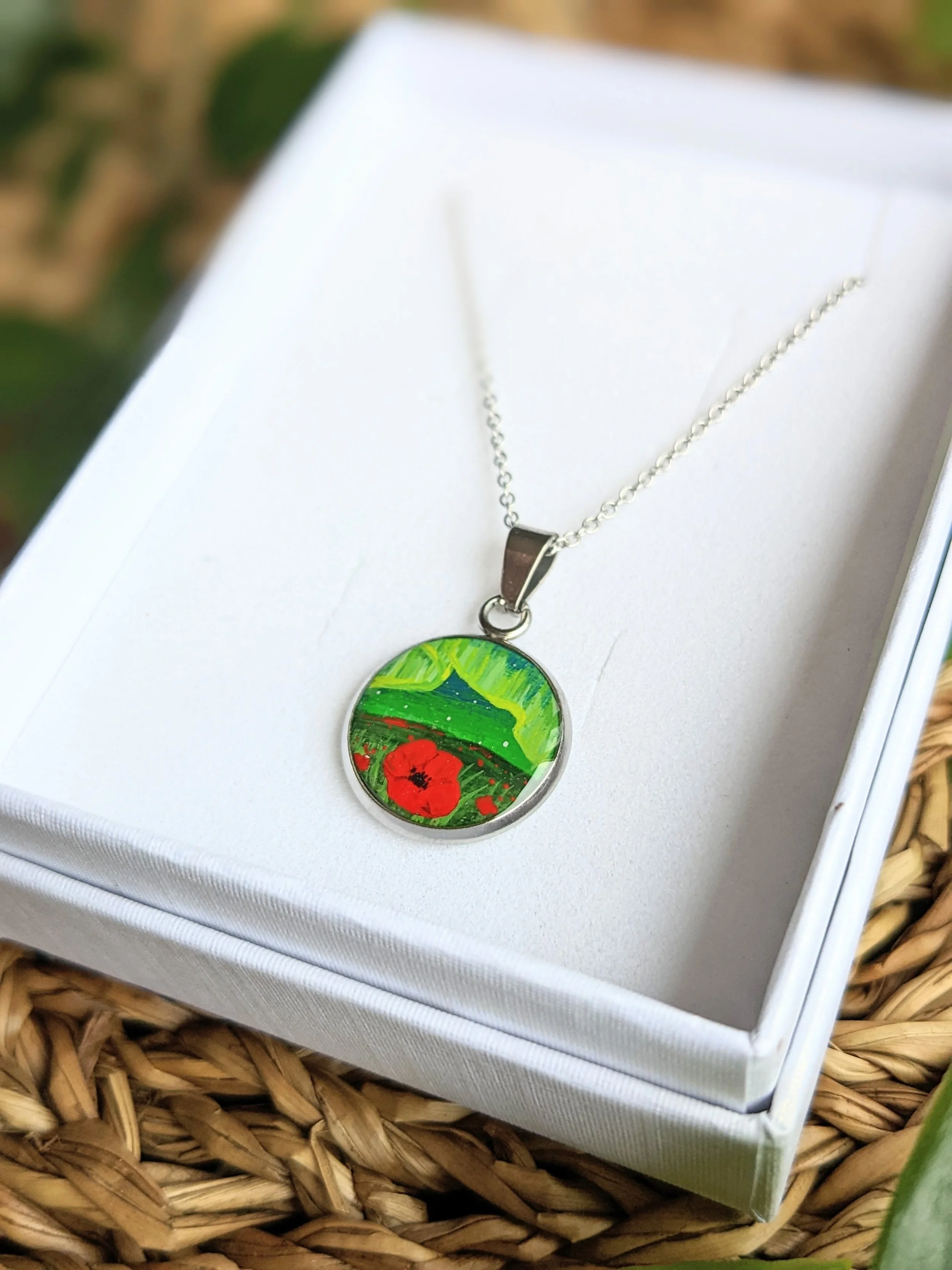 Custom hand-painted necklace featuring northern lights over a field of poppies (2022)